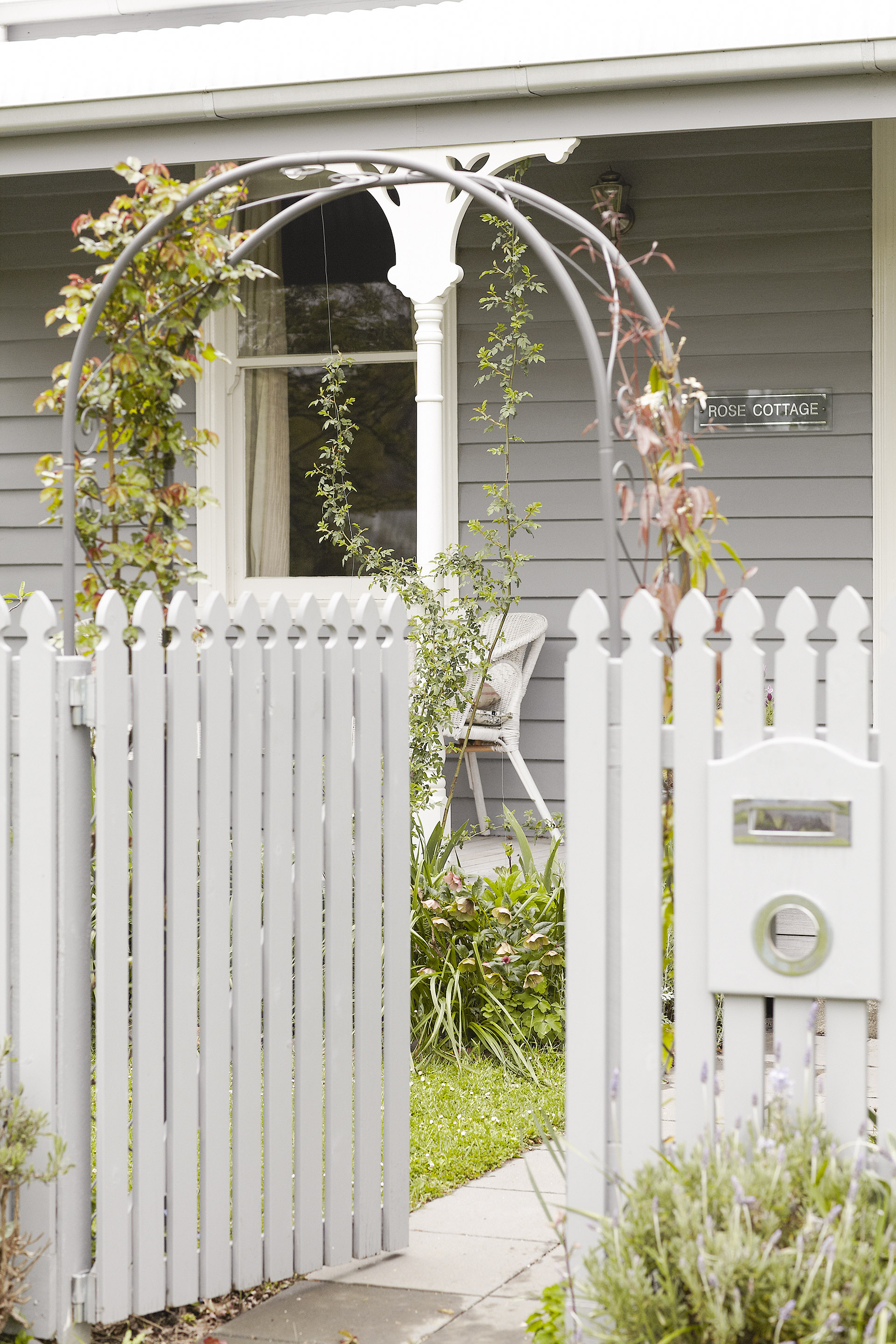 Grey cottage exterior with white picket fence.