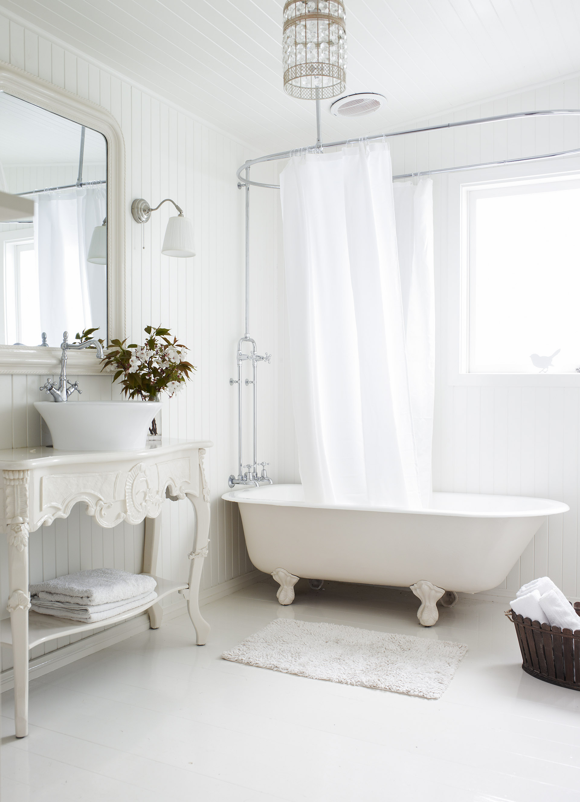 All white bathroom in a cottage with a claw foot cast iron tub.