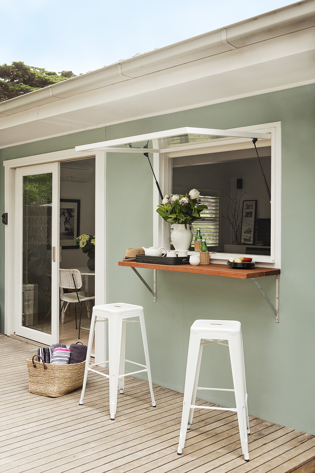Servery window opening to the deck of a renovated coastal weekender.