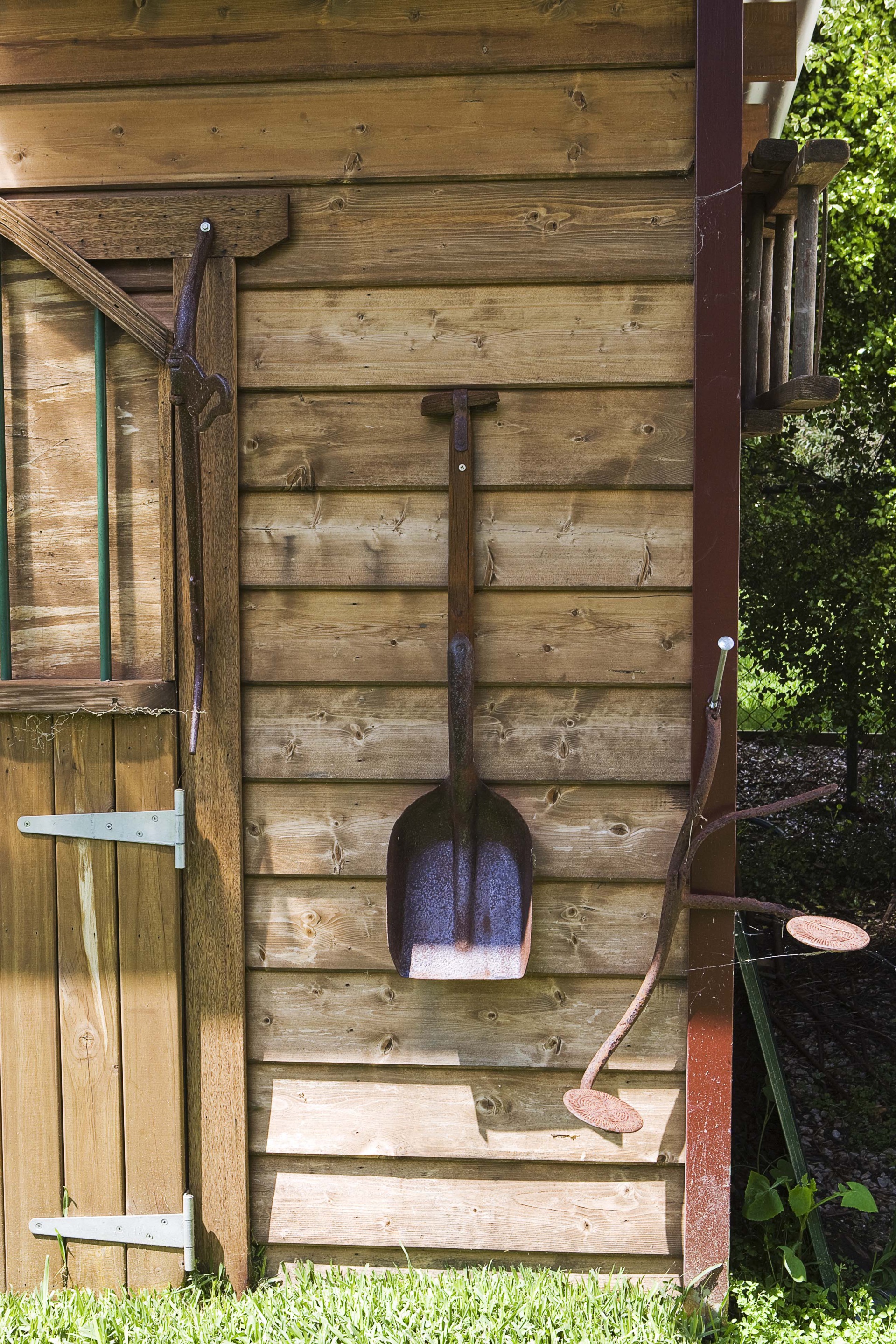Timber garden shed decorated with a rustic shovel.