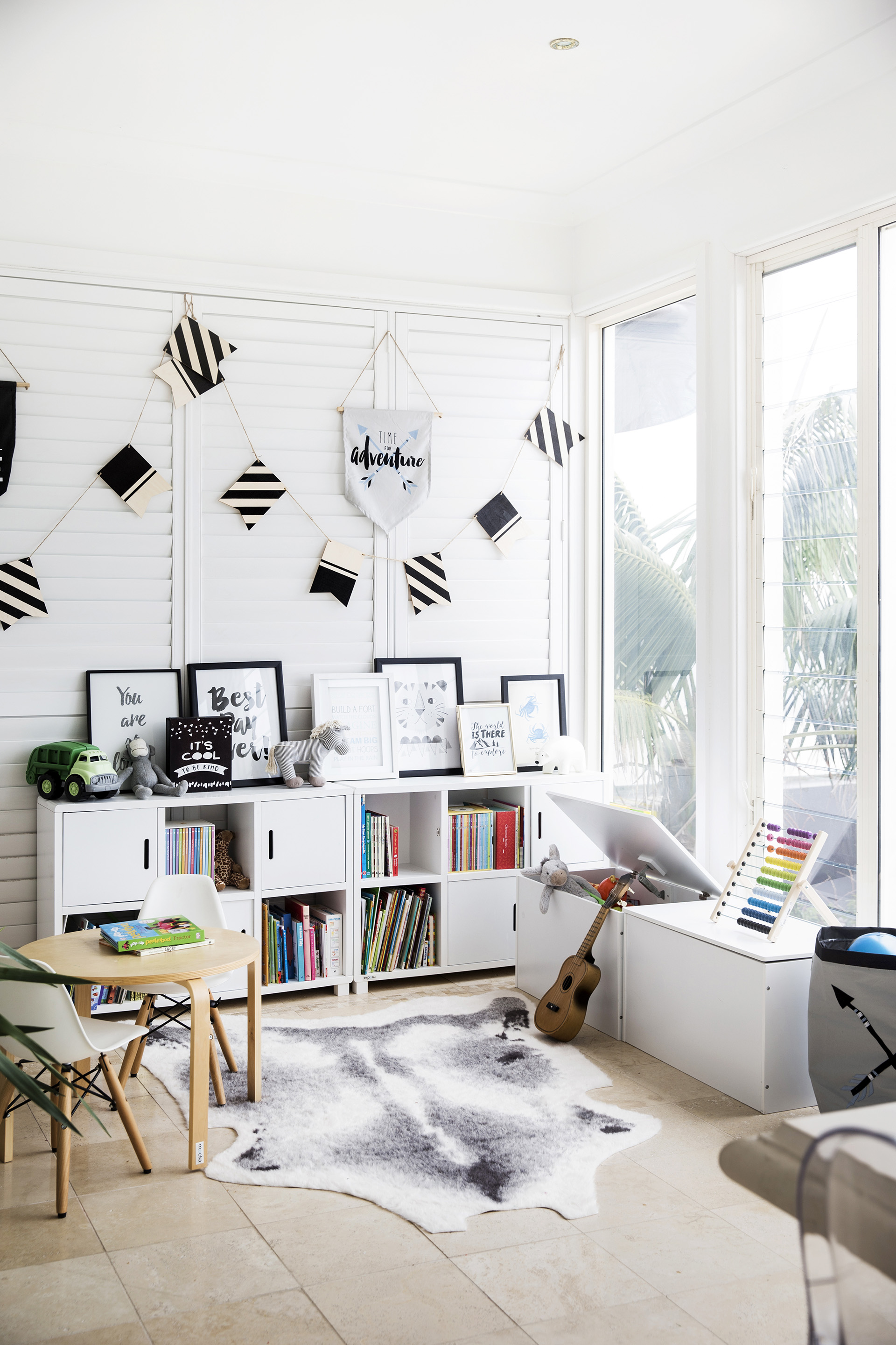 Shared boys' playroom with white cabinet and white toybox, floor to ceiling windows and bunting at the home of Charlie Albone and Juliet Love.