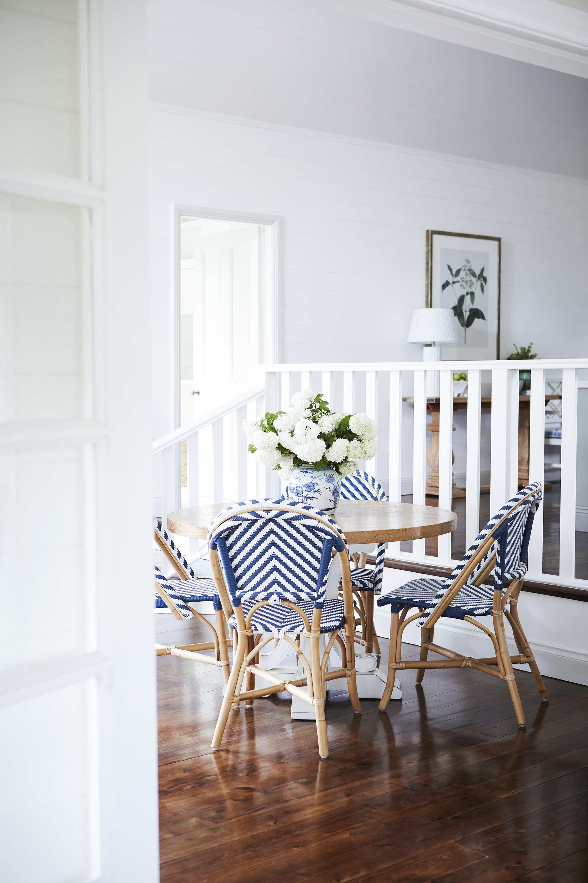Timber breakfast table surrounded by blue bistro chairs in a country-meets-Hamptons style home in Bowral.