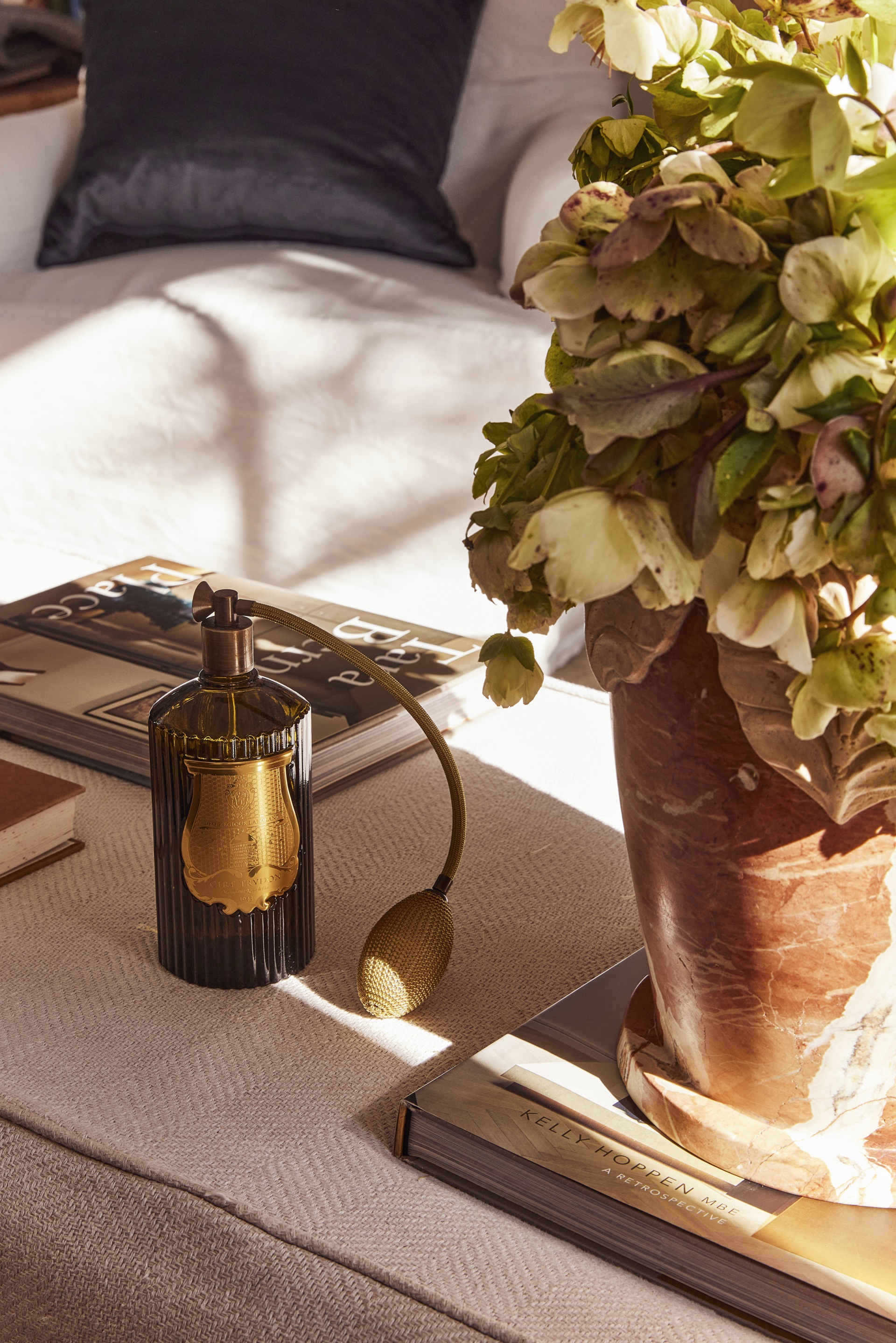 A vintage style ottoman with a planter and vintage perfume bottle.