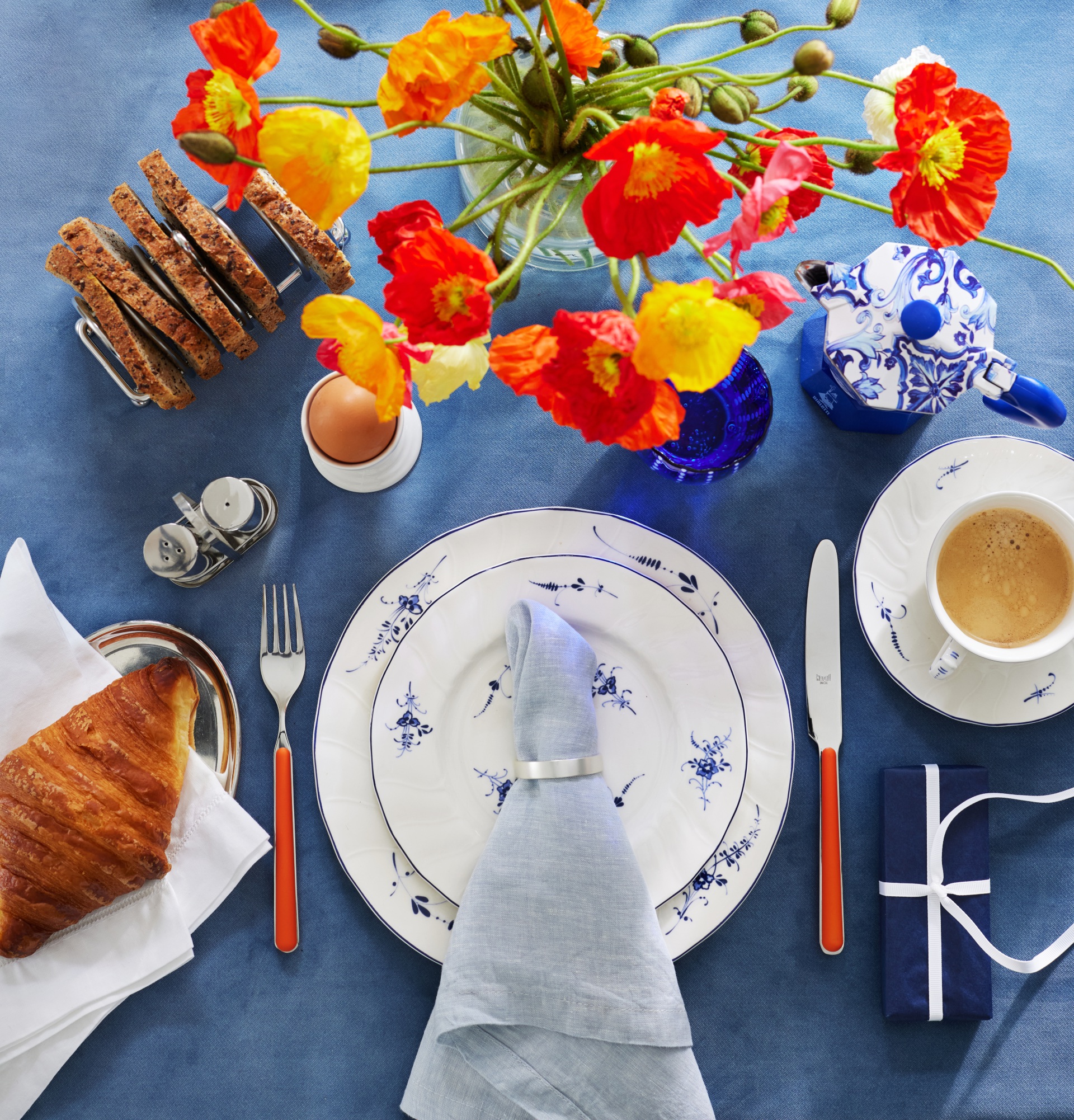 Christmas table decorations with blue table linen, colourful flowers and white plates