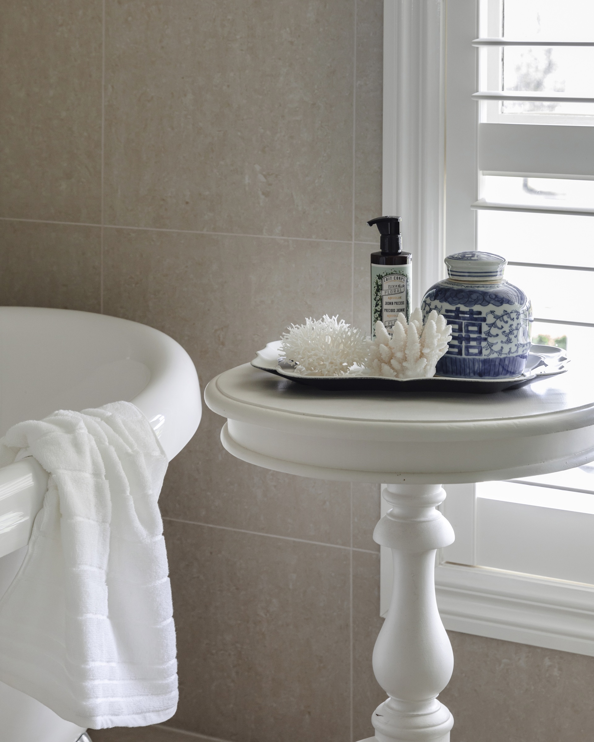 Decorative coral on a white side table by the bath tub.
