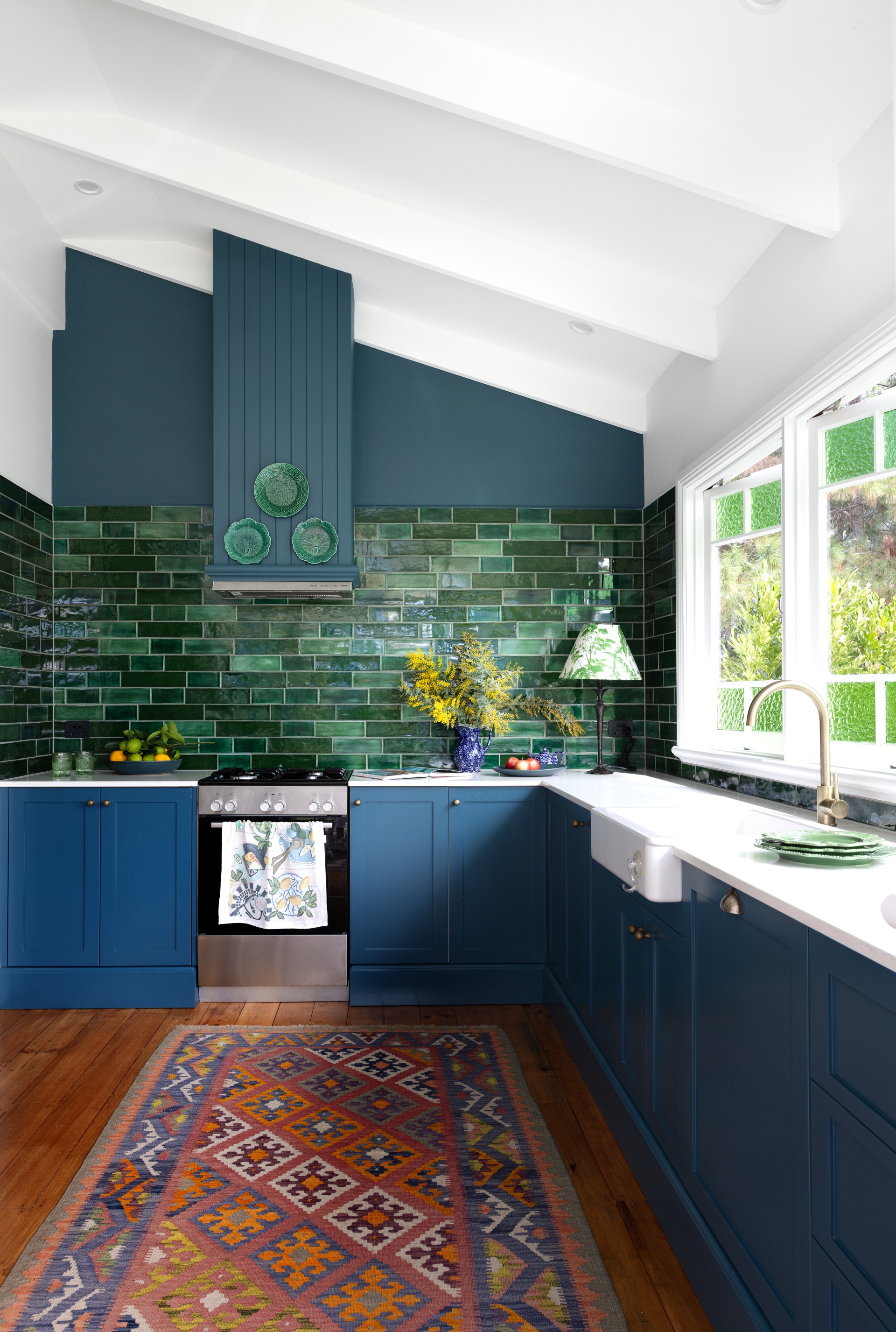 A blue and green modern country kitchen with a subway tile splashback.