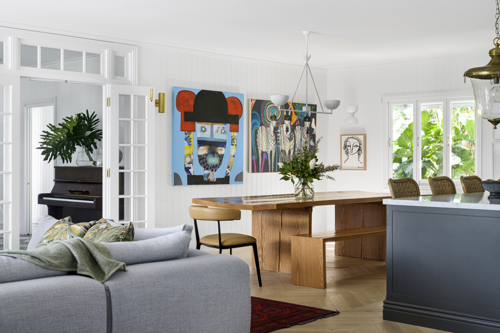 A dining room with a timber table, bright wall art and French open doors.