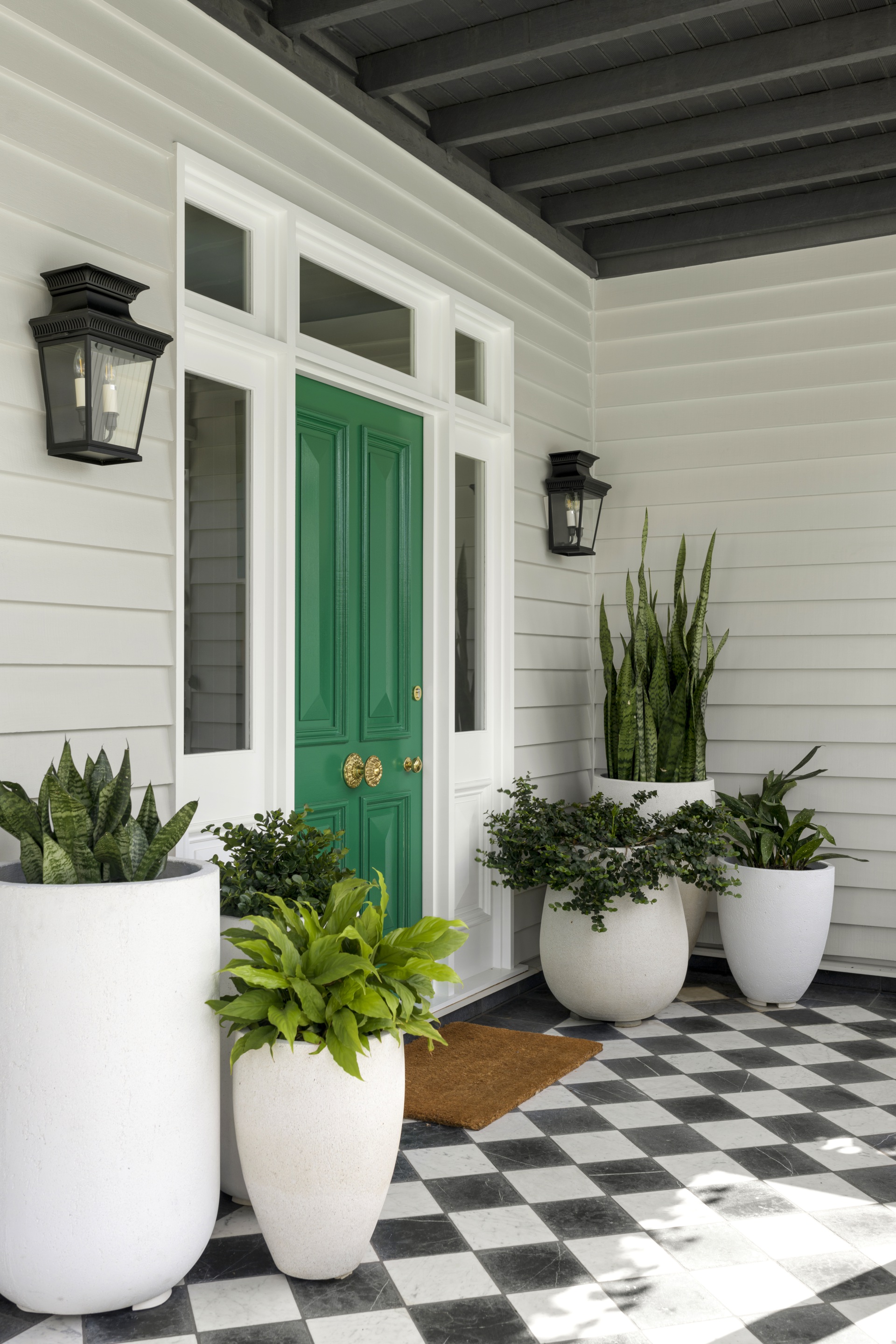 The front entrance with pot plants, green door and checked floor.