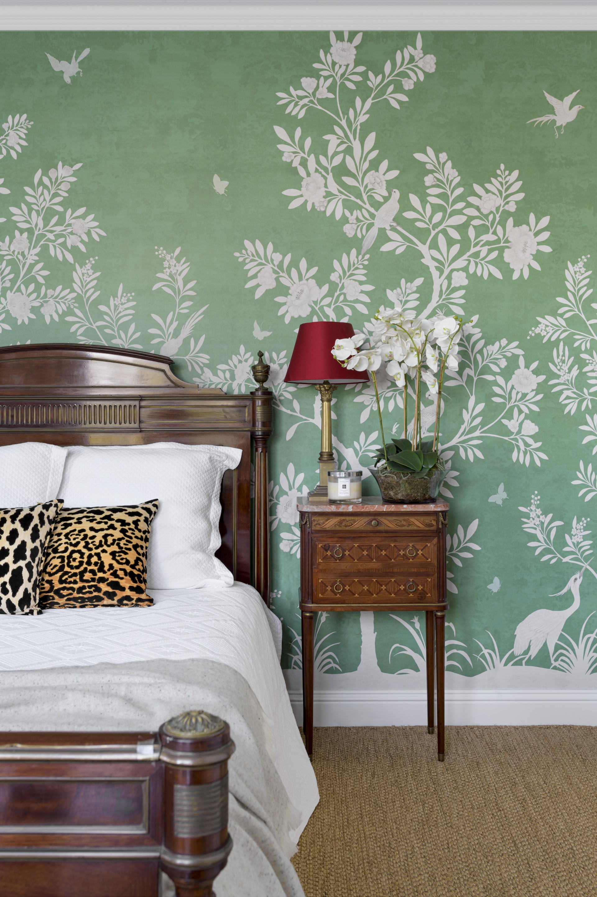 A guest bedroom with green floral wallpaper and timber bed.