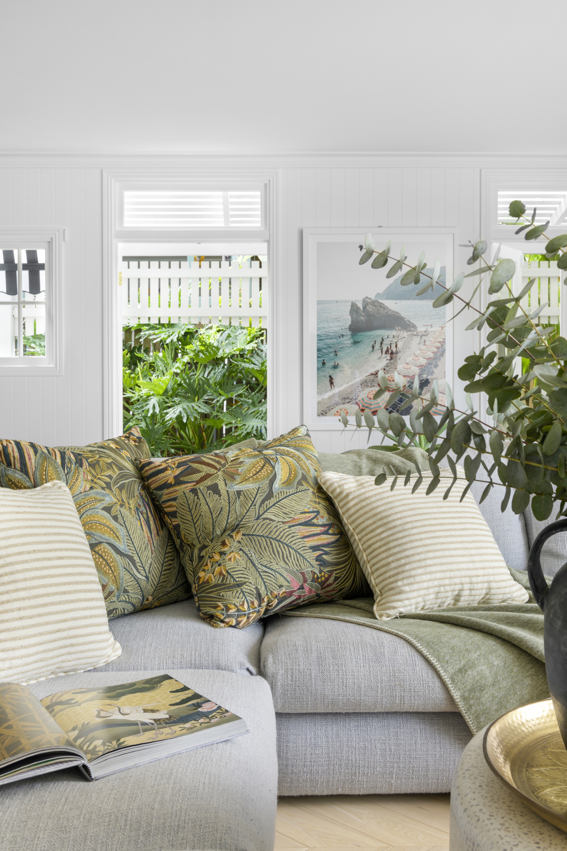 A grey sofa with green tropical cushions.
