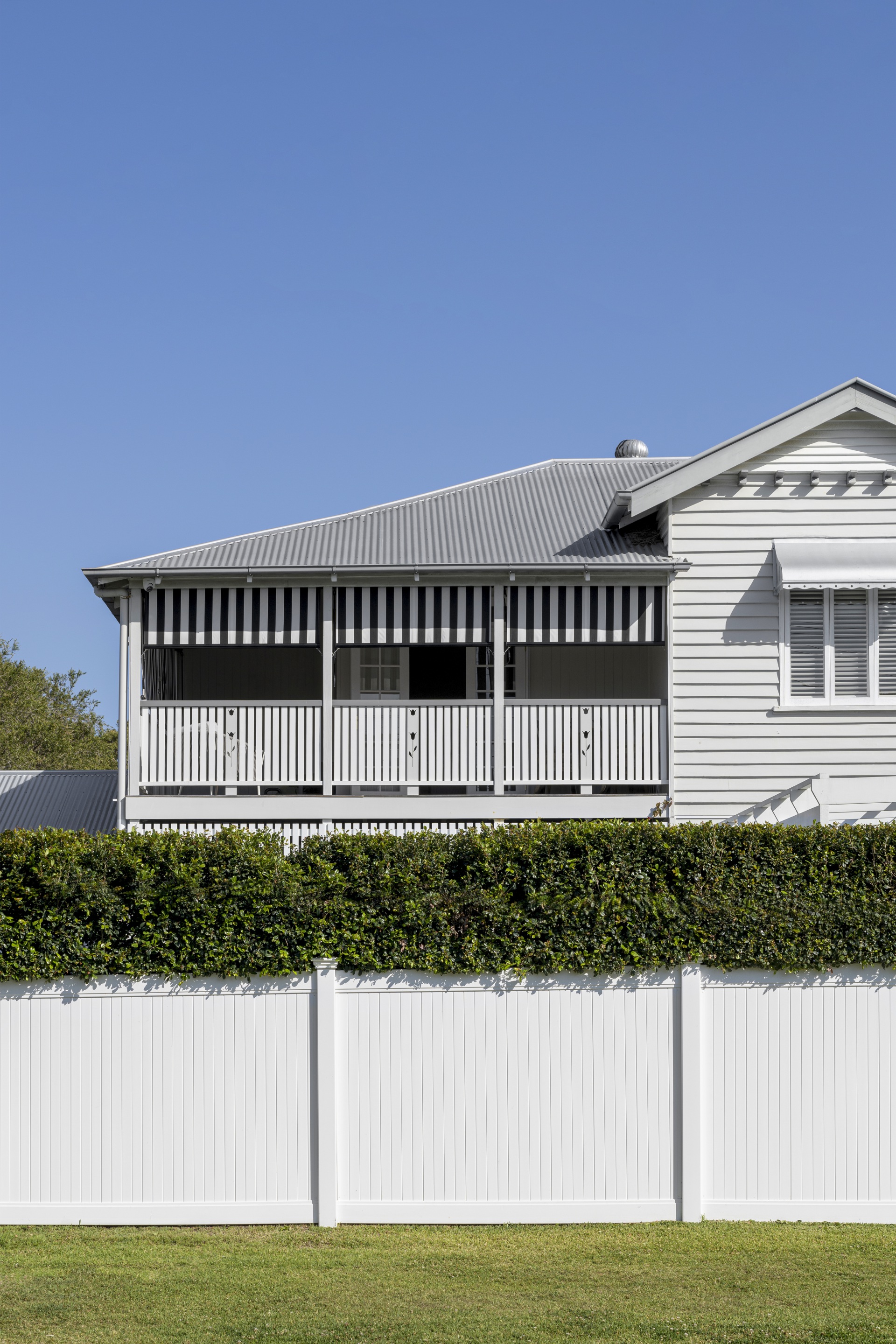 A white two-storey weatherboard cottage with a balcony.