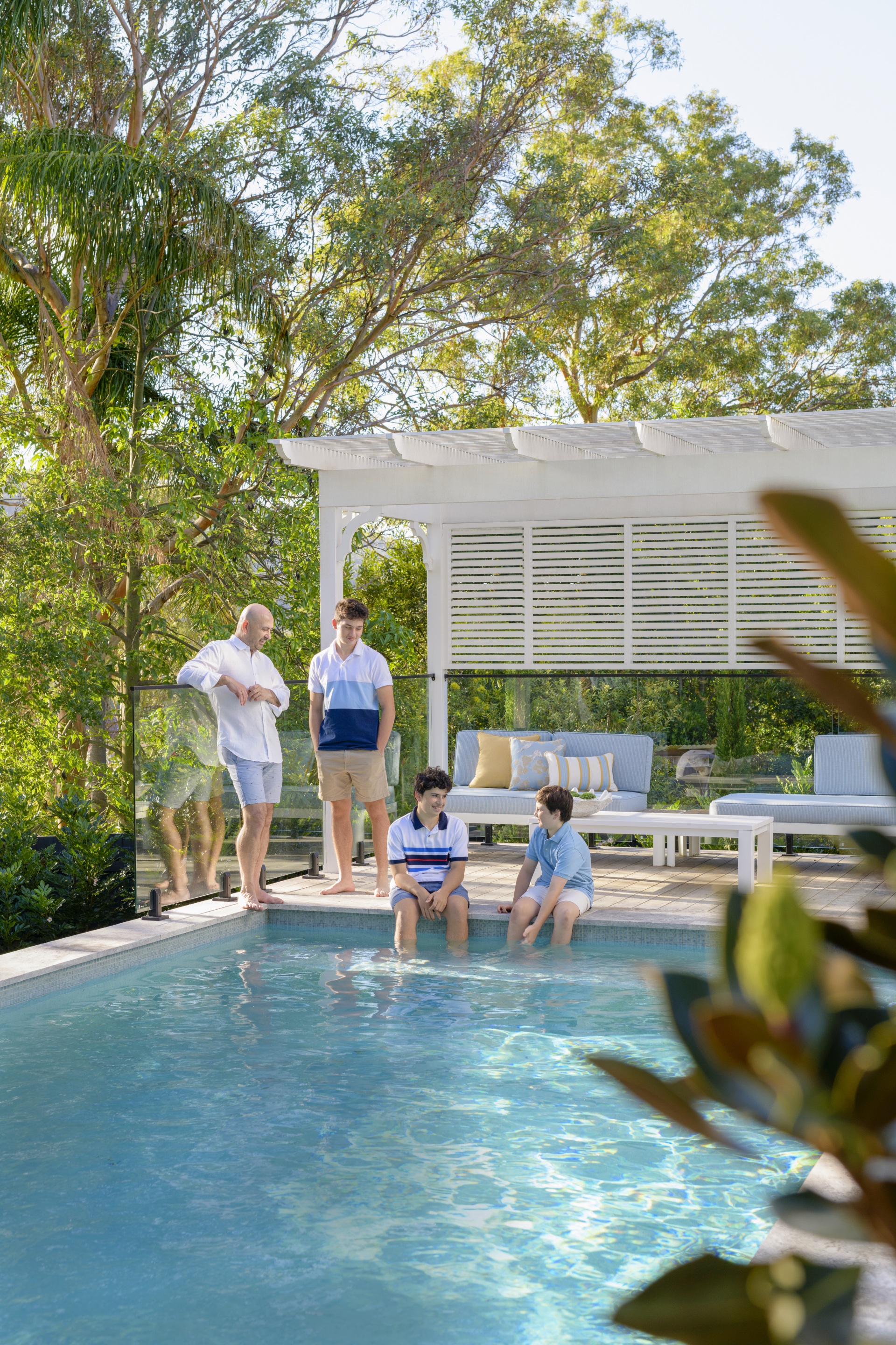 A family sitting by the pool beneath a white cabana.