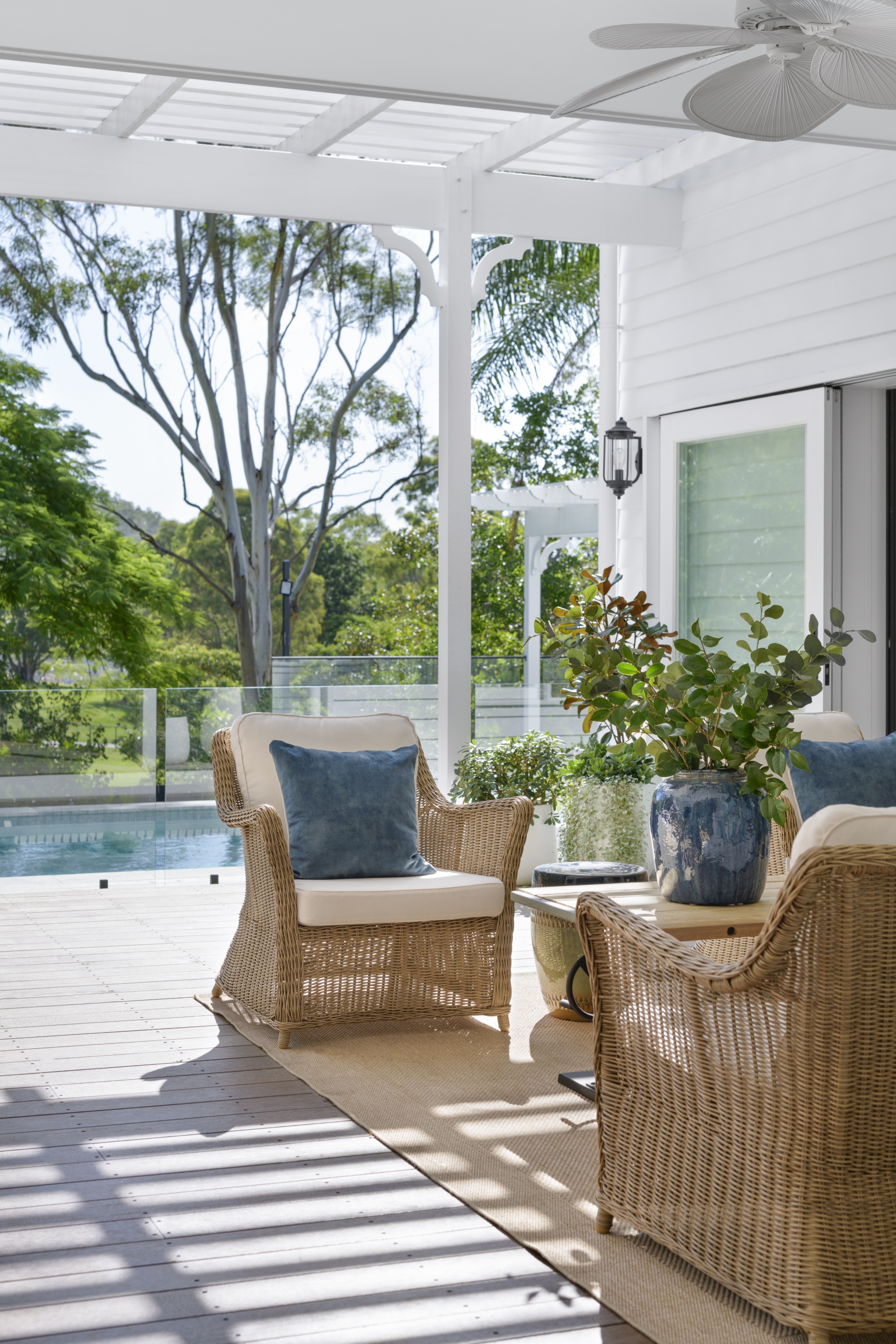 Wicker chairs in the white outdoor alfresco area by the pool.