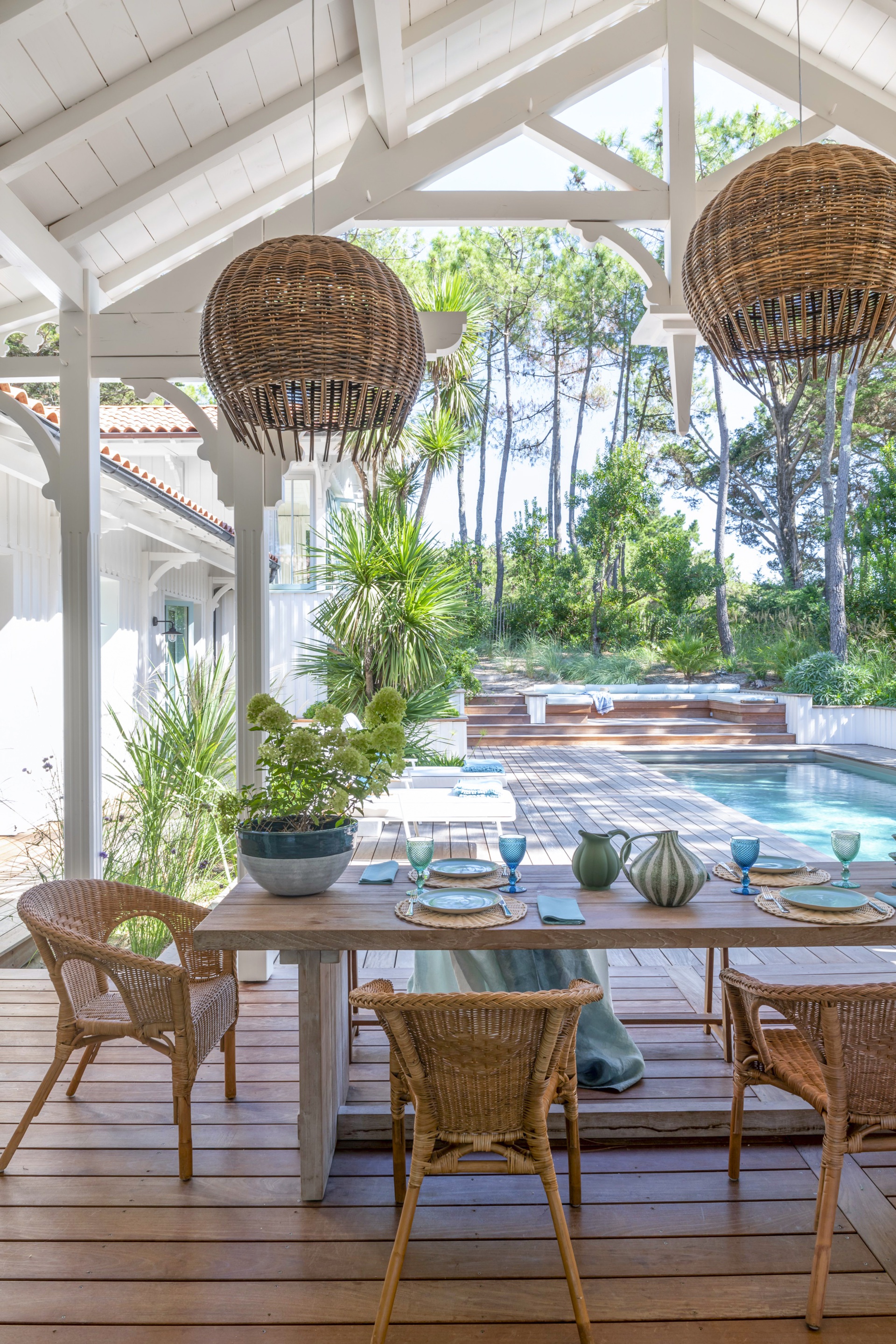 An outdoor alfresco area with wicker furniture overlooking a pool.
