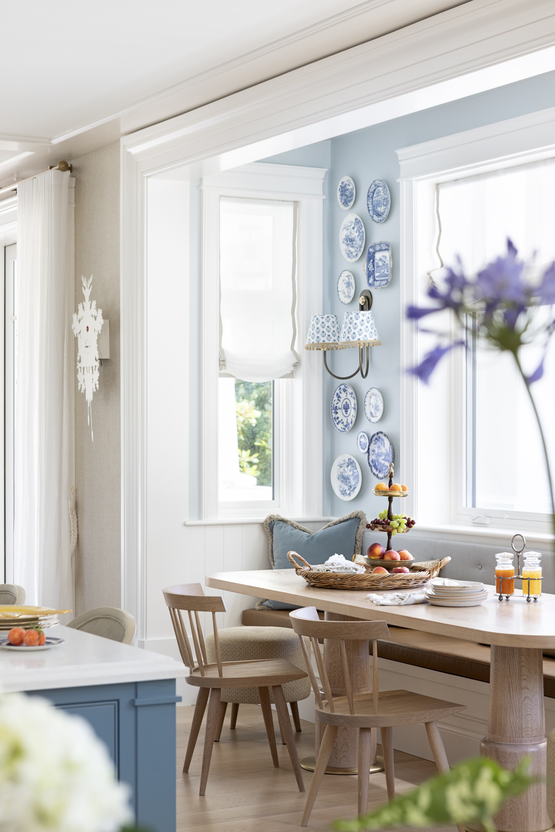 A timber breakfast nook below a wall gallery of decorative plates.