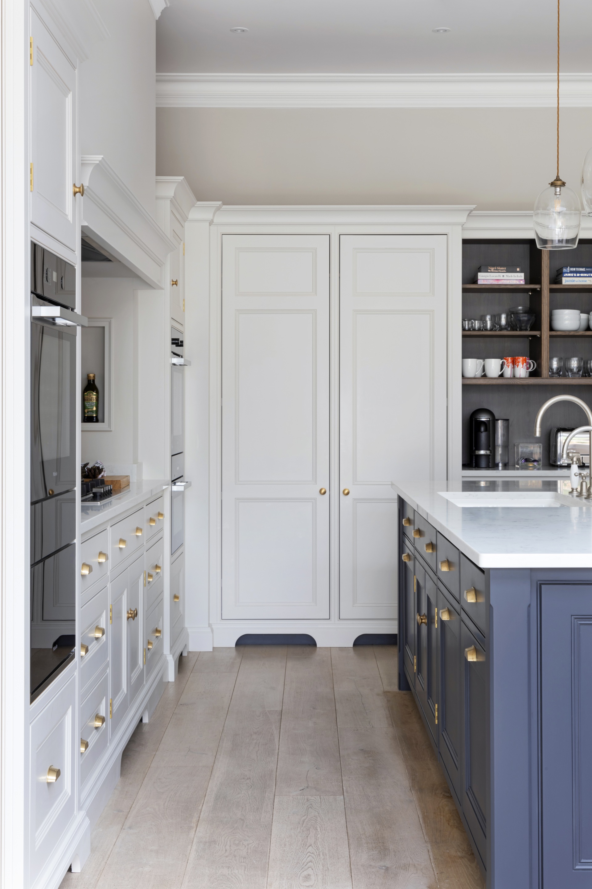A white and blue kitchen with classic shaker cupboards and gold handles.
