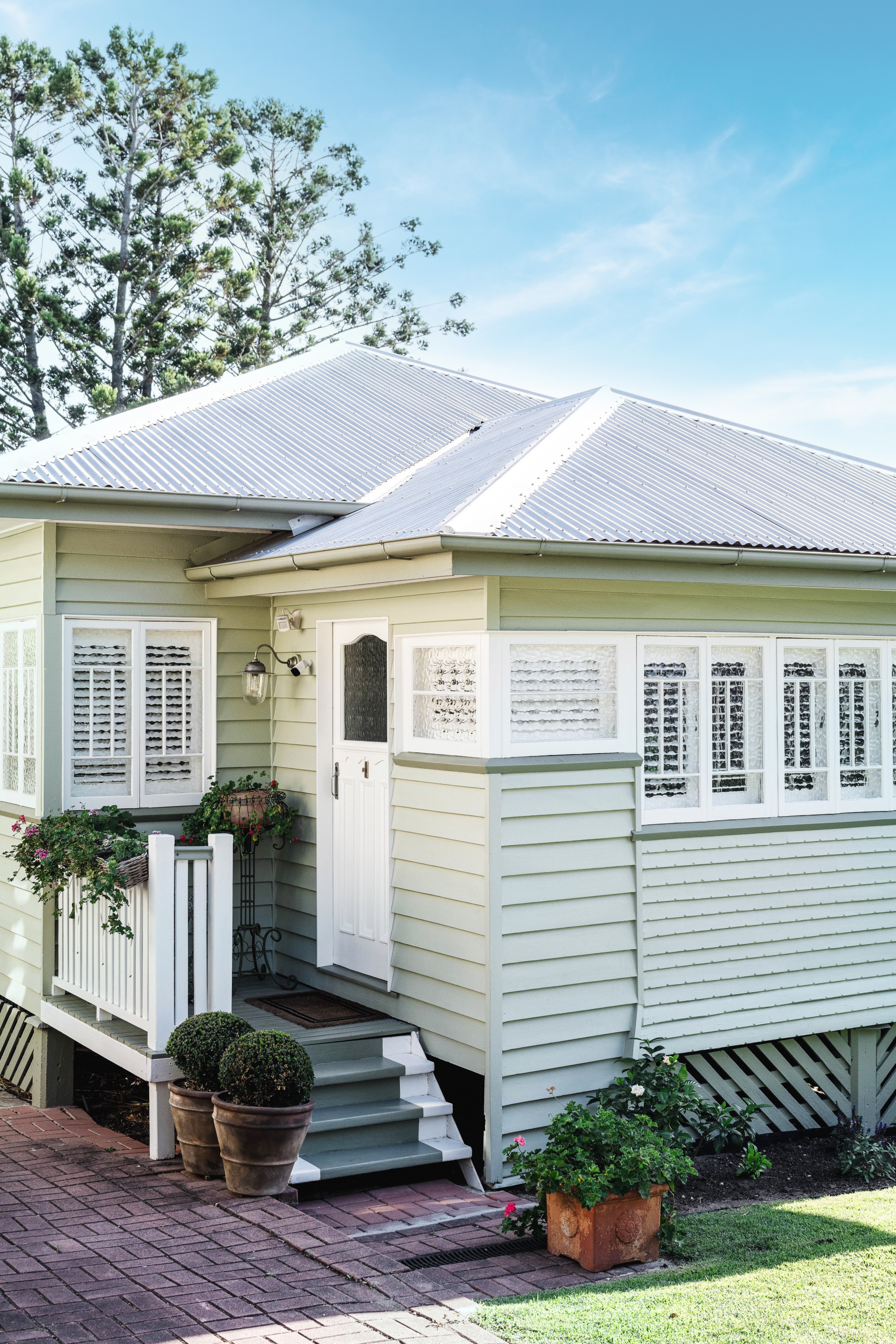 A 1930s Queenslander with light green timber cladding.
