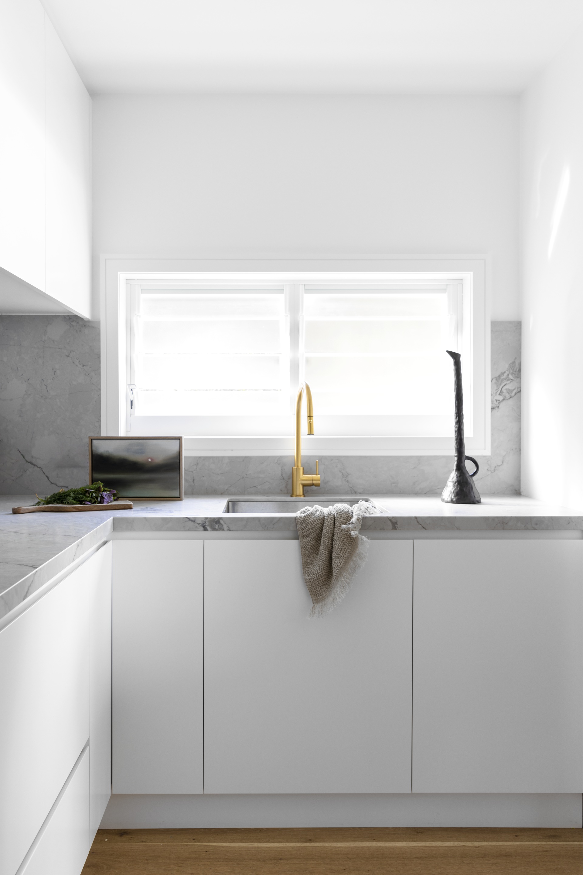 A white and grey marble butler's pantry with gold tapware.
