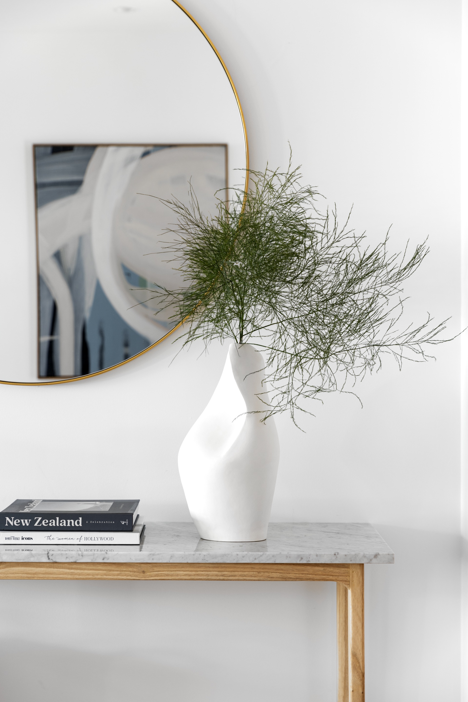 A sculpted white vase on a grey marble console.