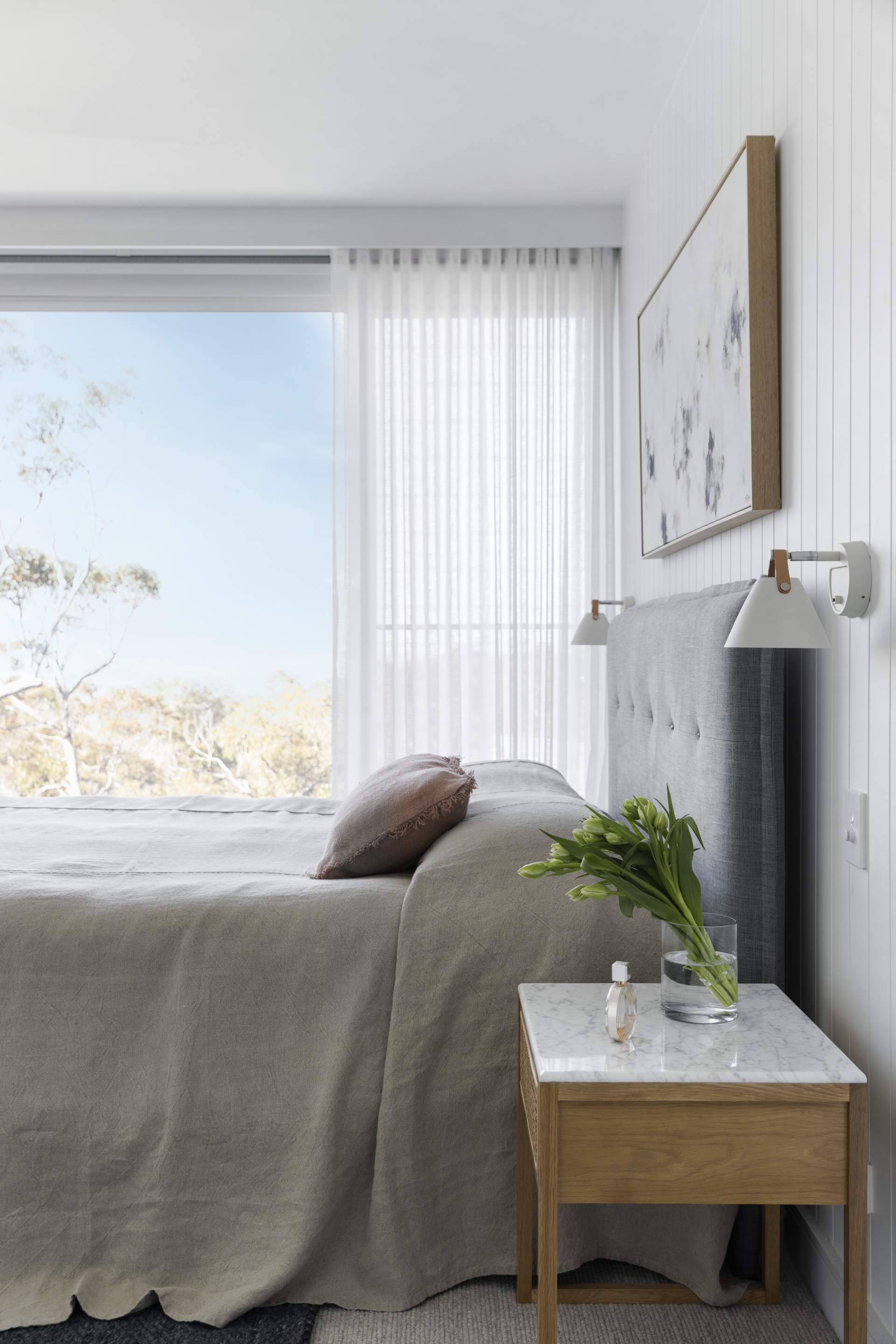 The main bedroom with an abstract artwork over a grey bed.