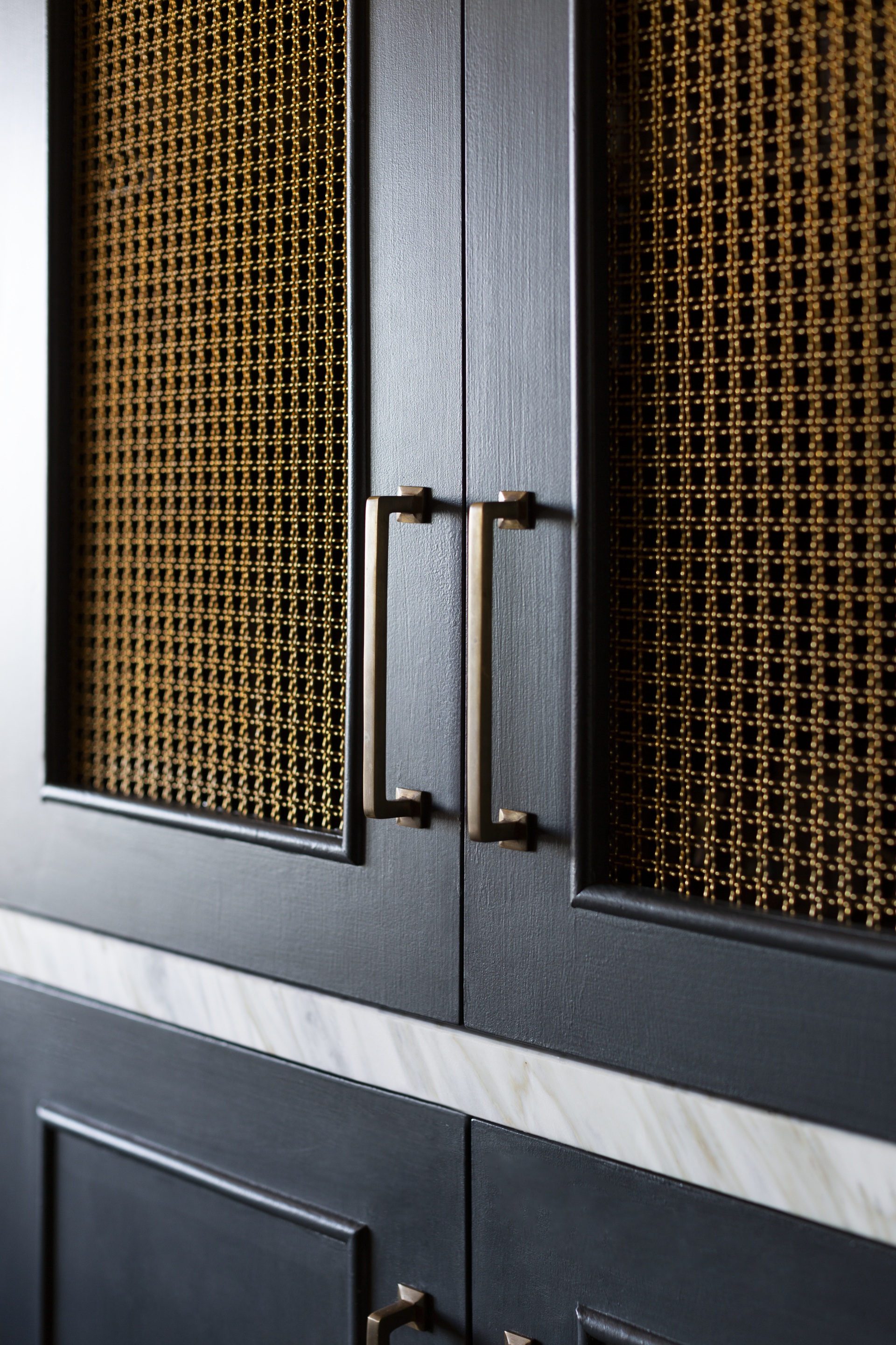 A navy kitchen cabinet with bronze mesh inlays.