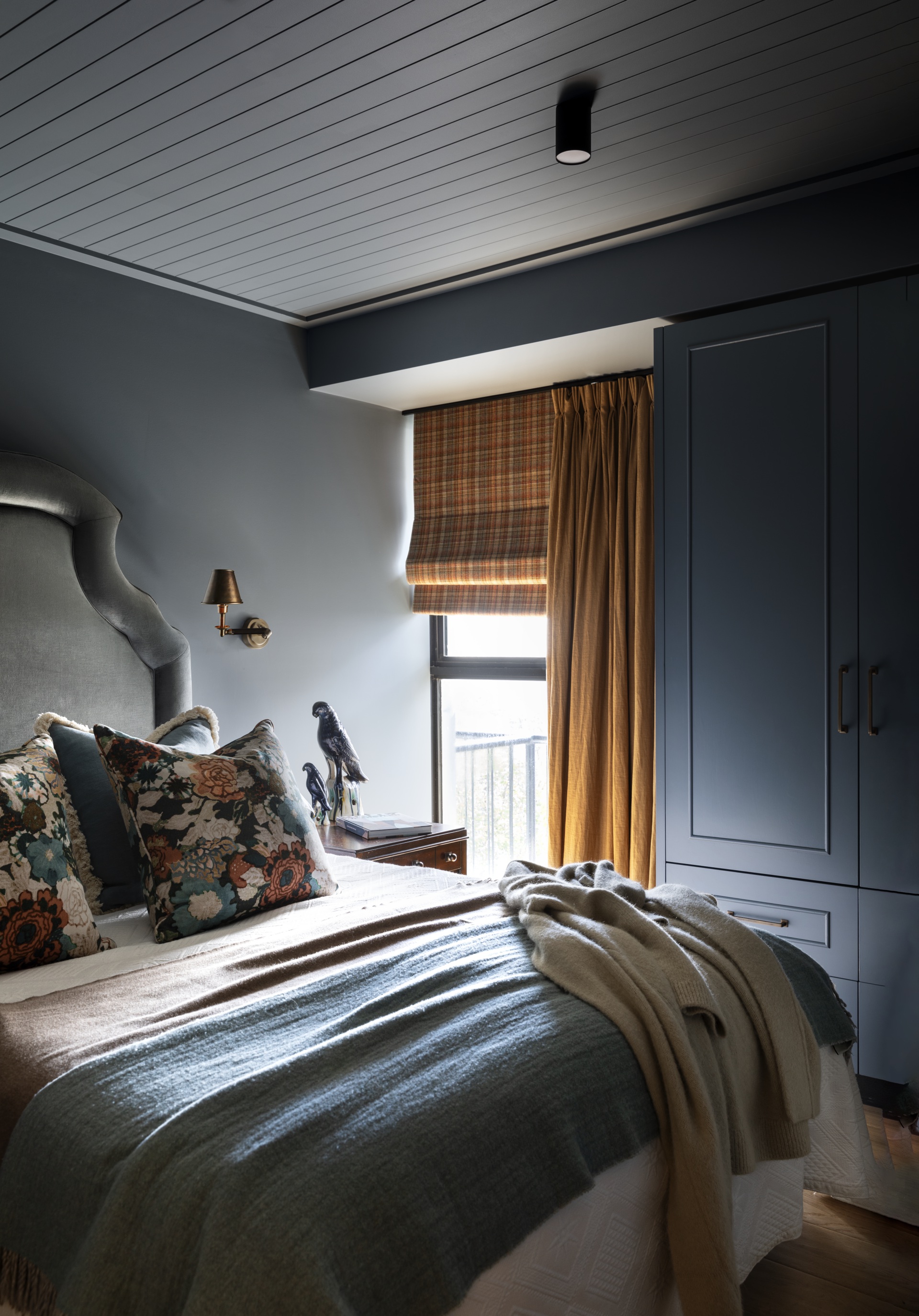 A moody blue bedroom with mustard yellow curtains.