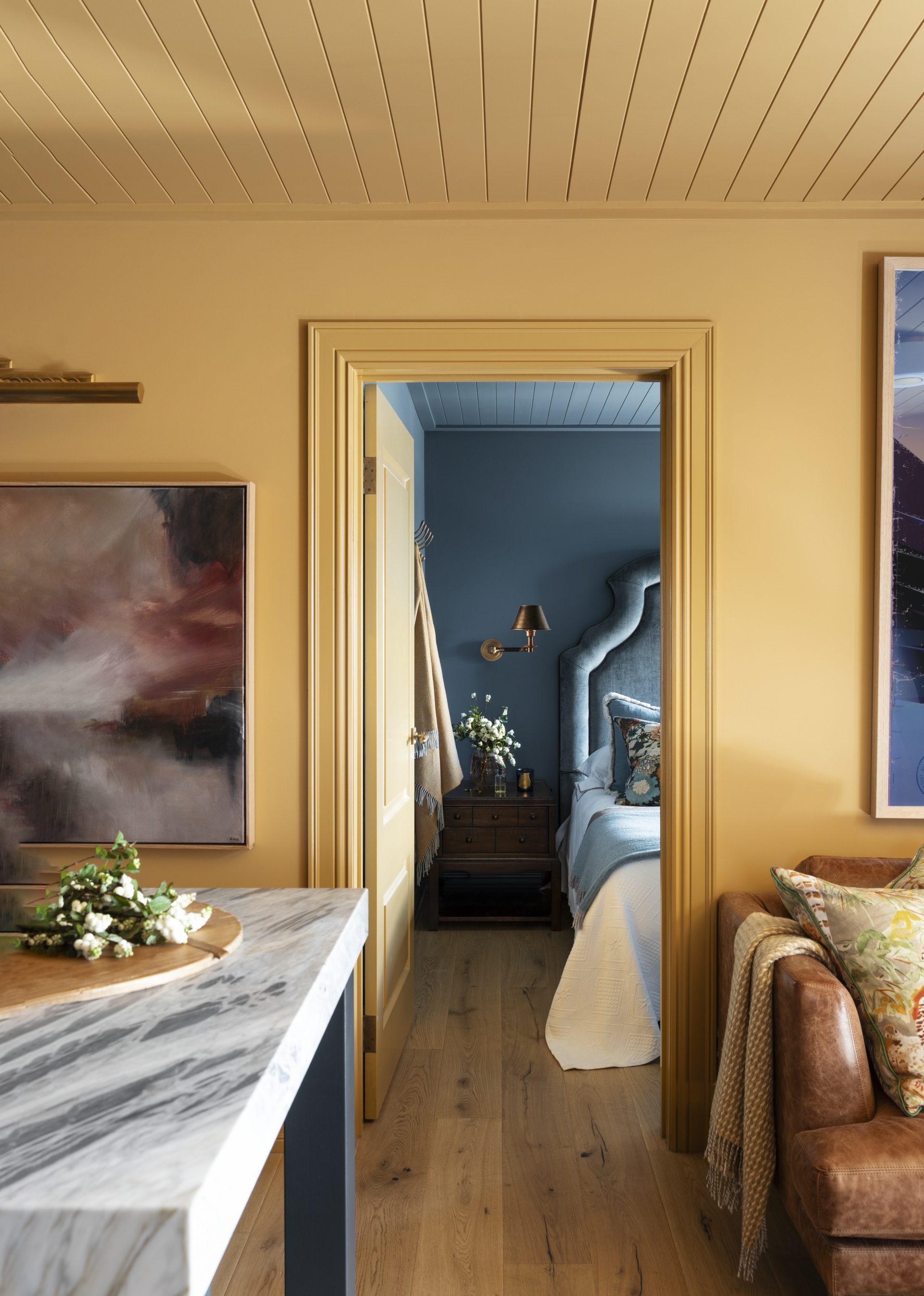 A mustard yellow living room with a leather sofa and marble table.