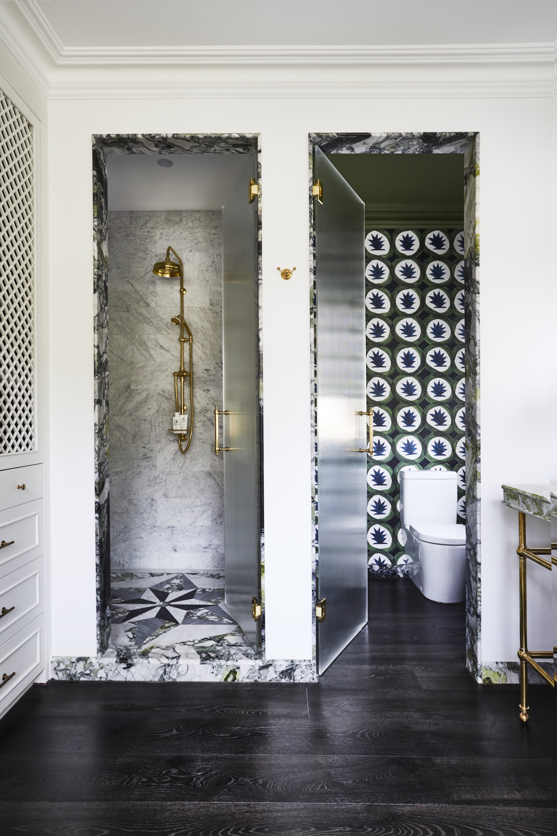 An ensuite with a side-by-side marble doorways to a shower and toilet.