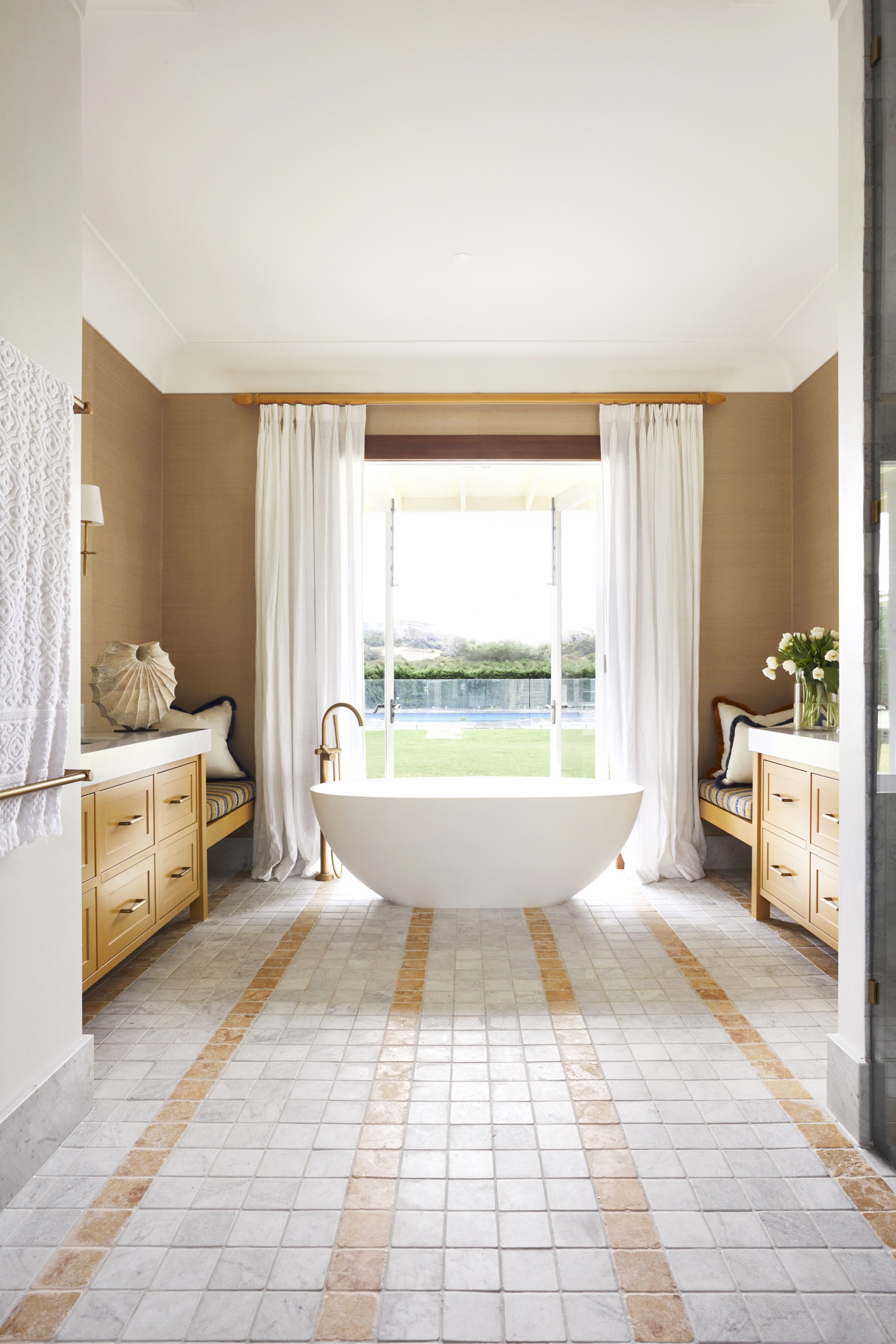 Tumbled stone tiles leading to a freestanding bath by a window.
