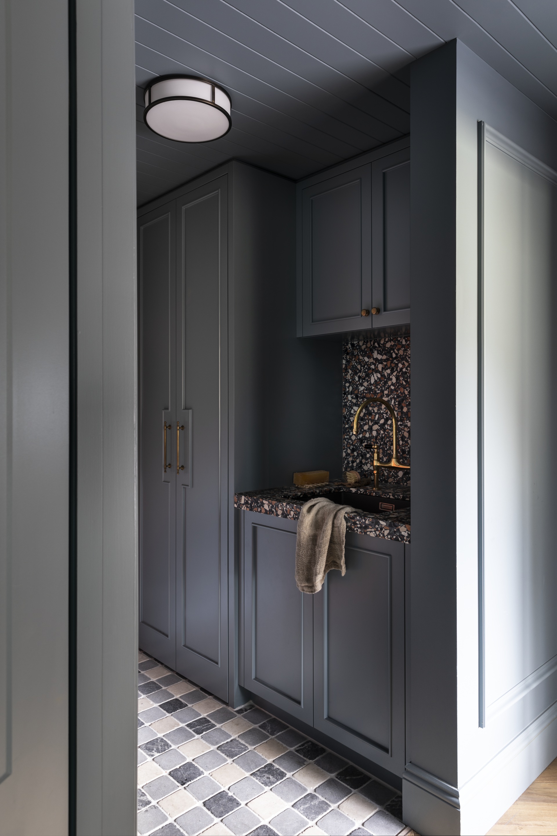 A laundry in teal with a checked tile floor and vj panelling.