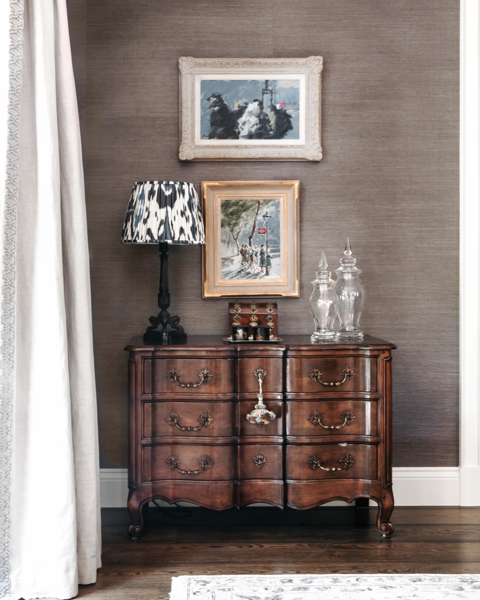 A timber vintage-style set of drawers beneath framed art.