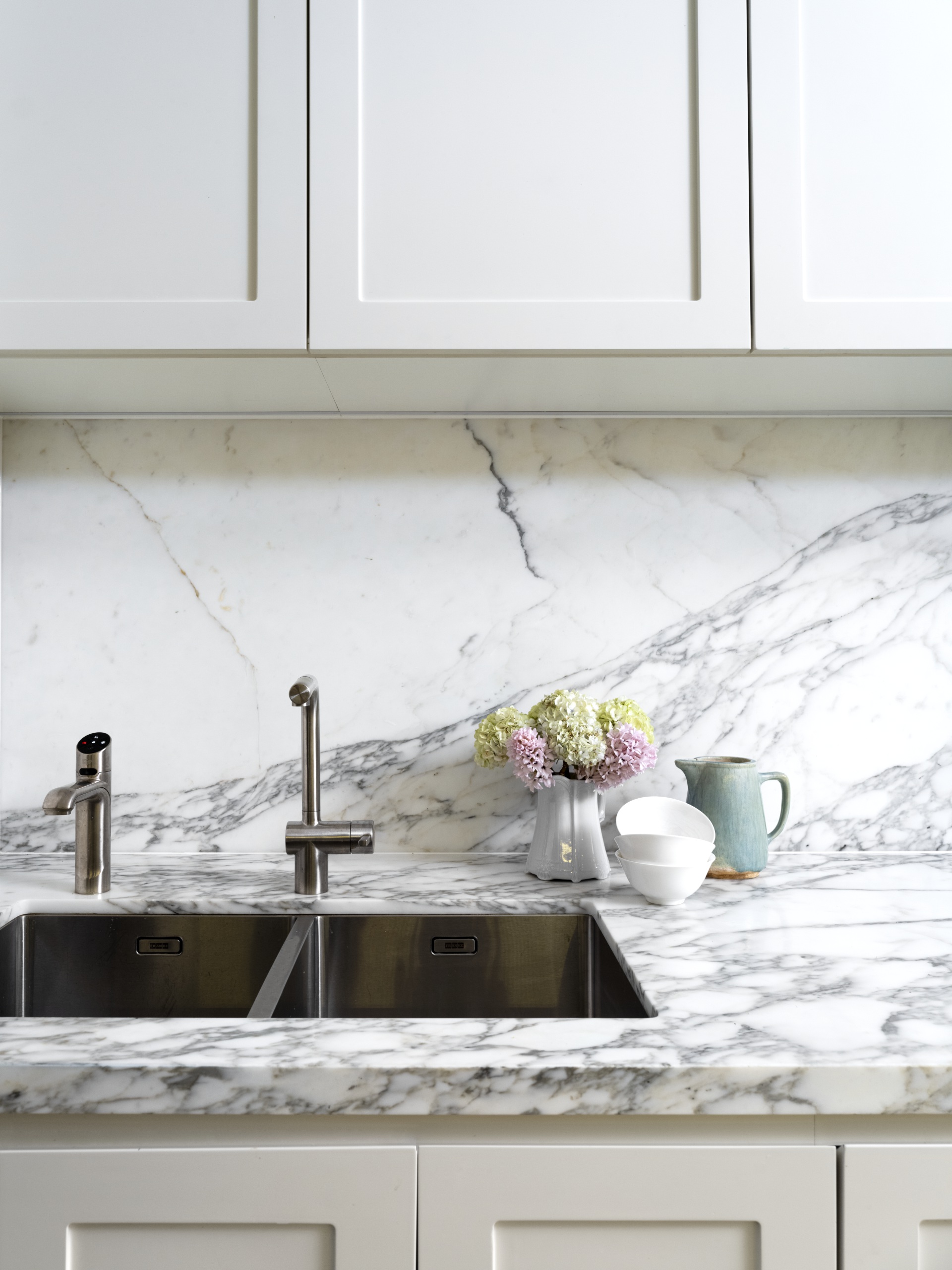 A sink and marble benchtop below shaker cabinets.