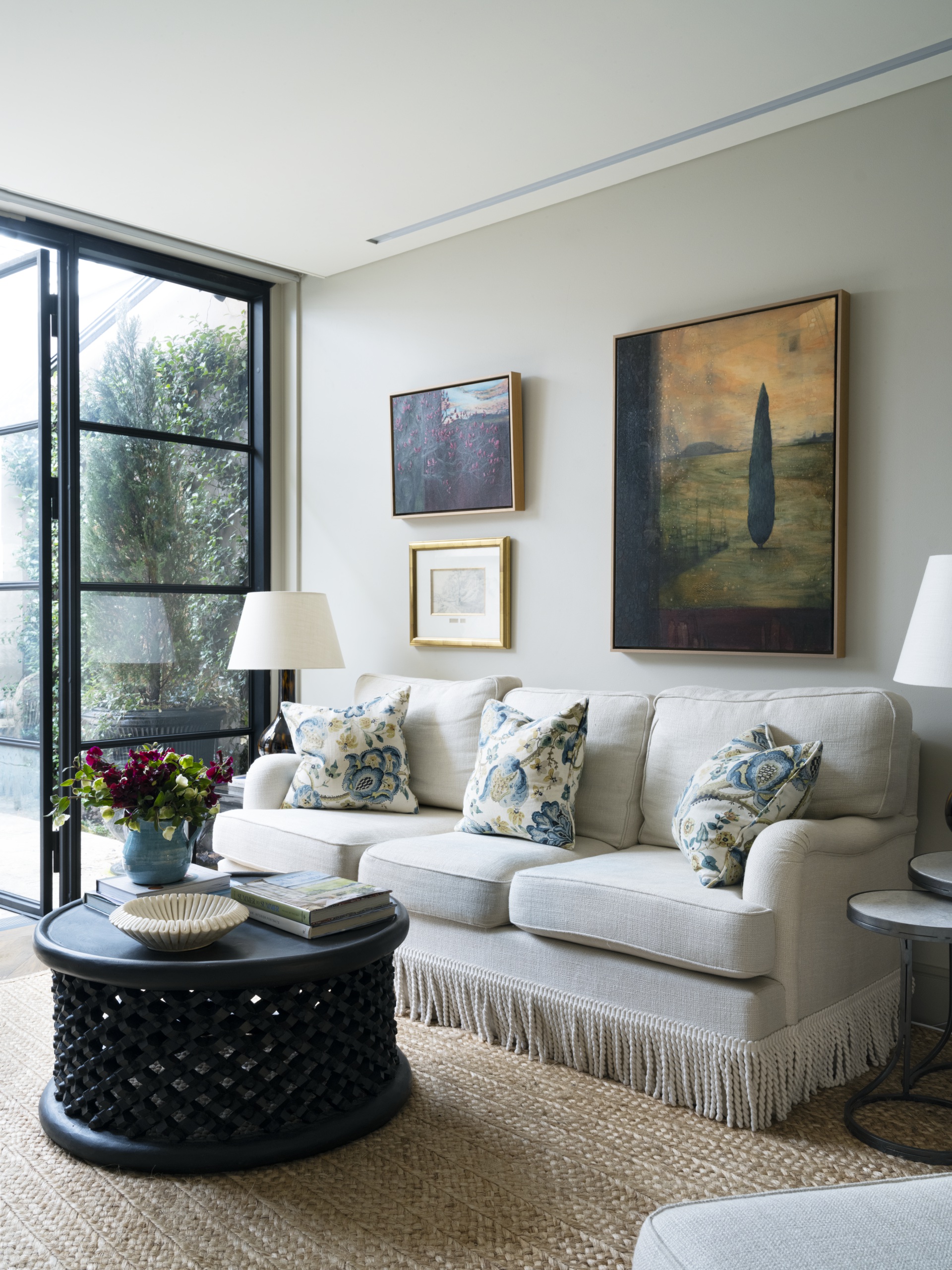 A white sofa and black weaved coffee table on a natural jute-style rug.