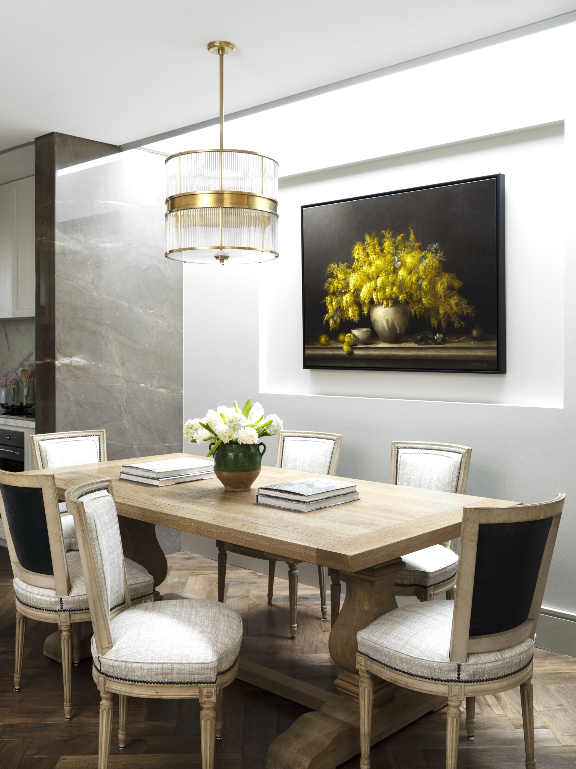 A dining room with a classic timber table, rounded light pendant and floral artwork.