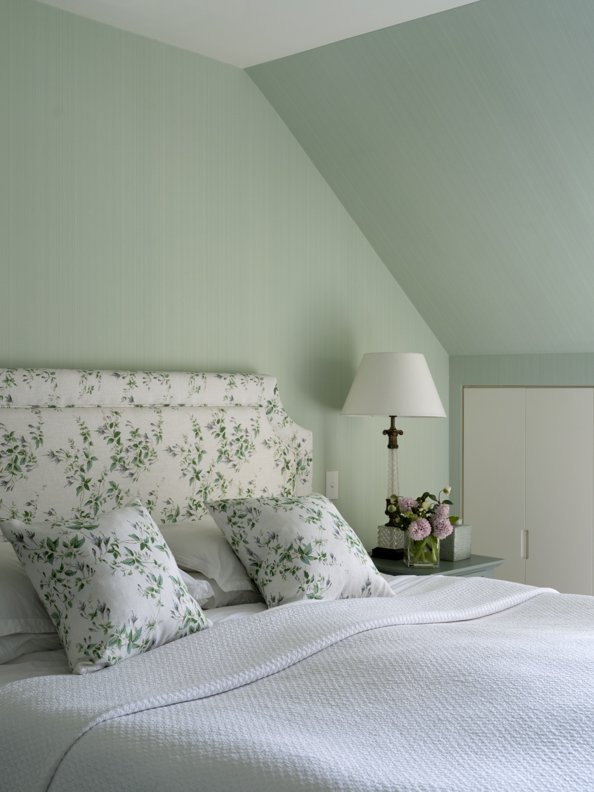A classic style main bedroom in pastel green with floral accents.