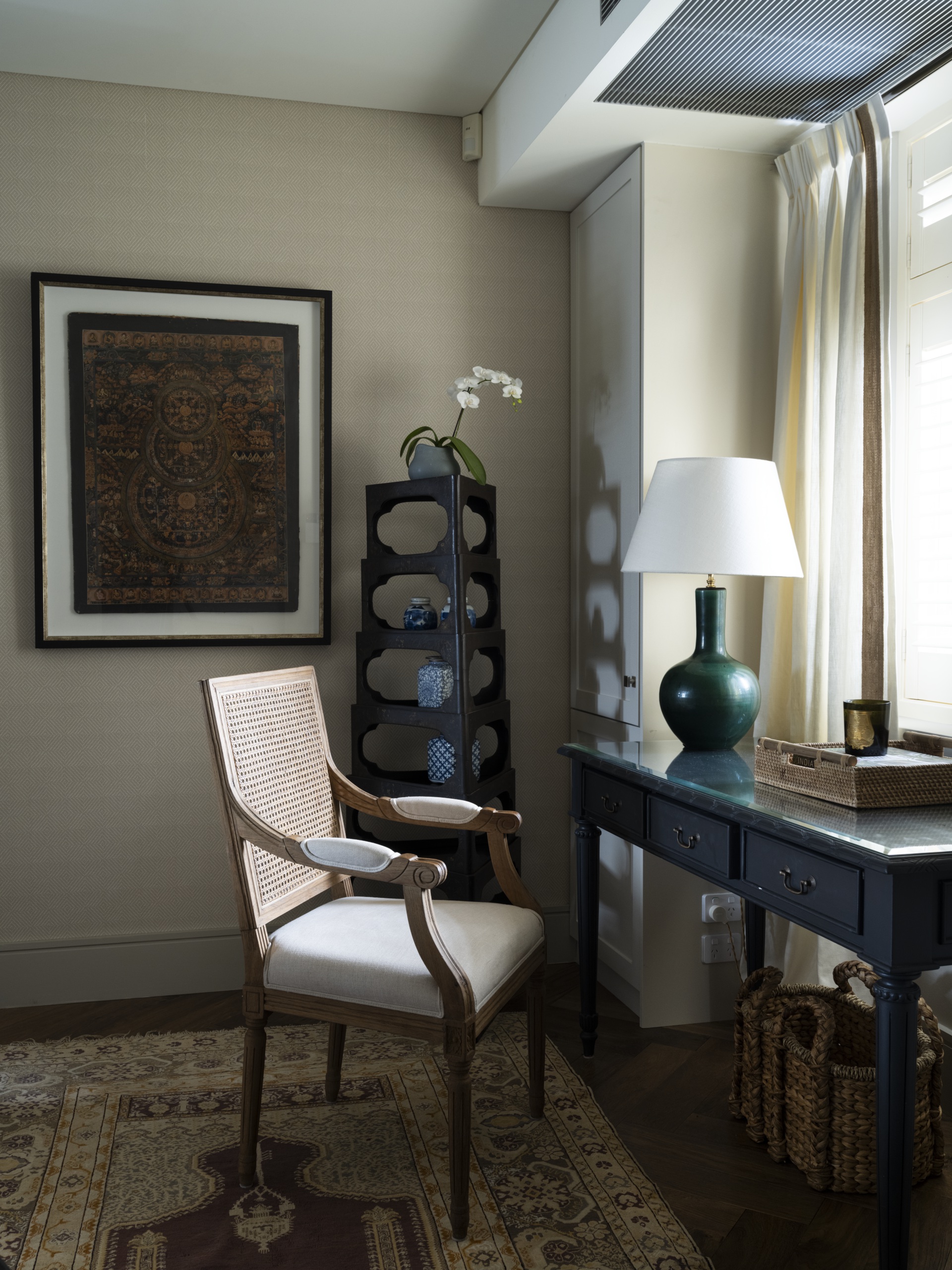 A study with vintage furniture and a Nepalese framed artwork.