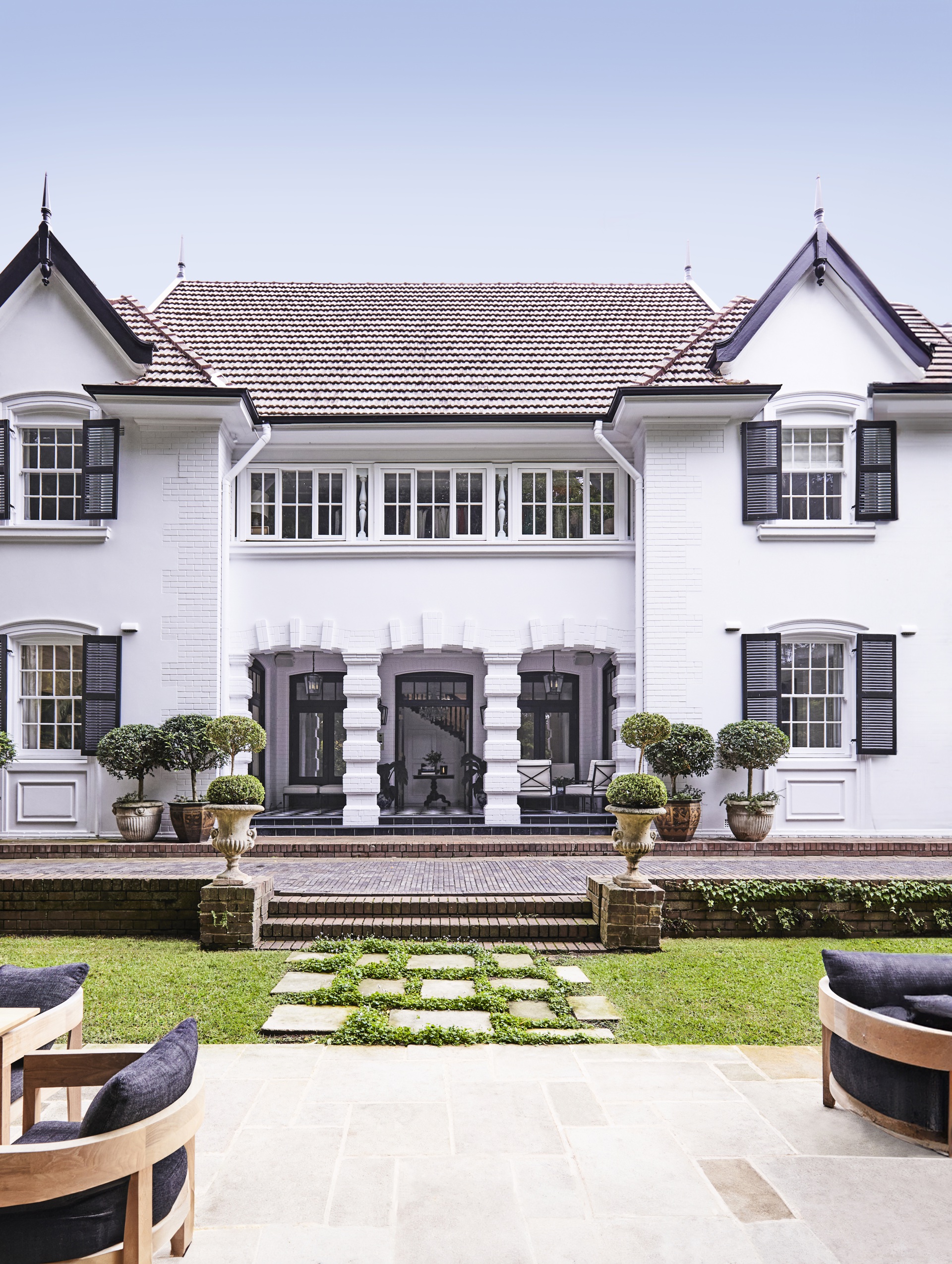 A classic white two-storey home with topiary plants out the front.