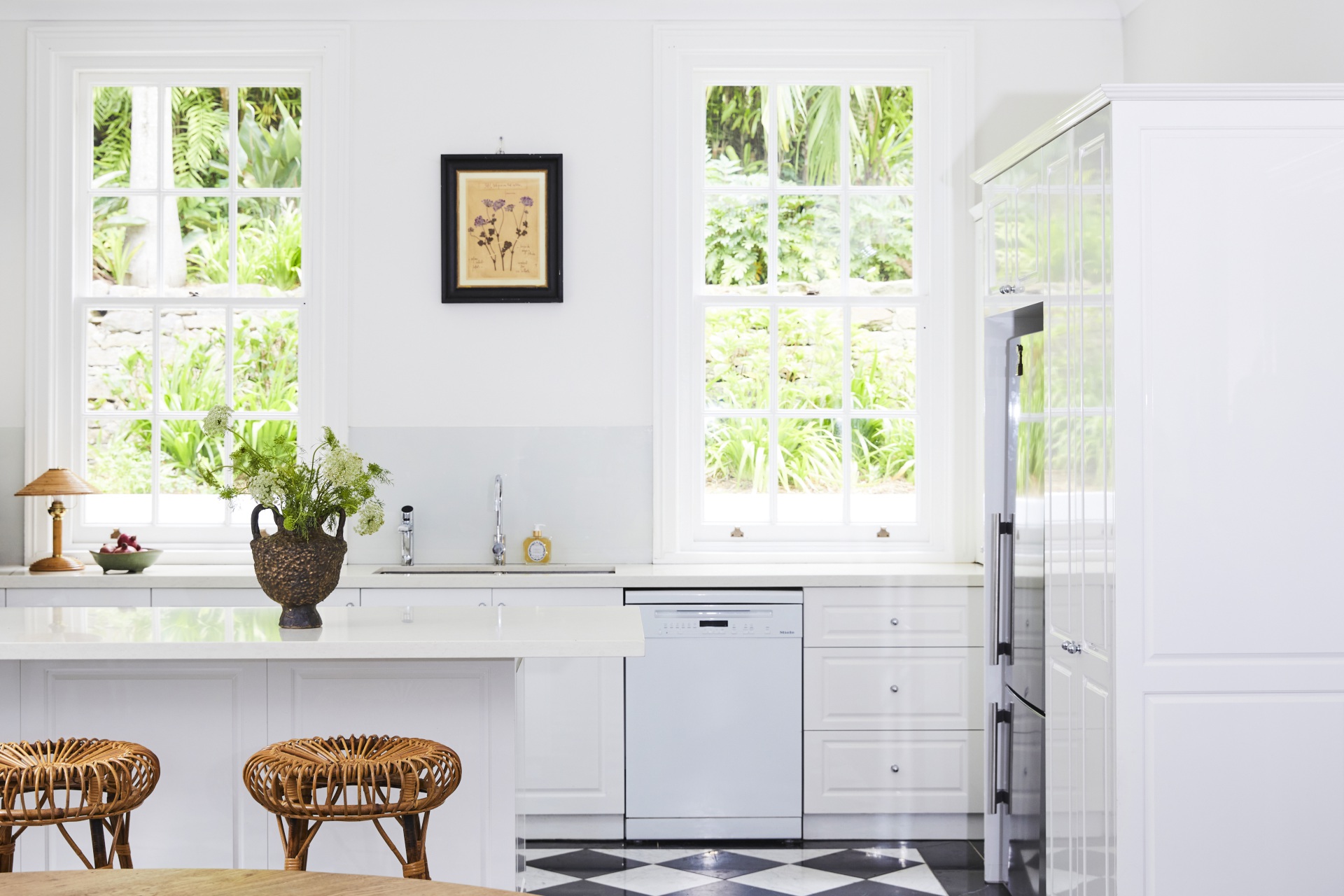 An all-white kitchen with shaker-style cabinets and a checked floor.