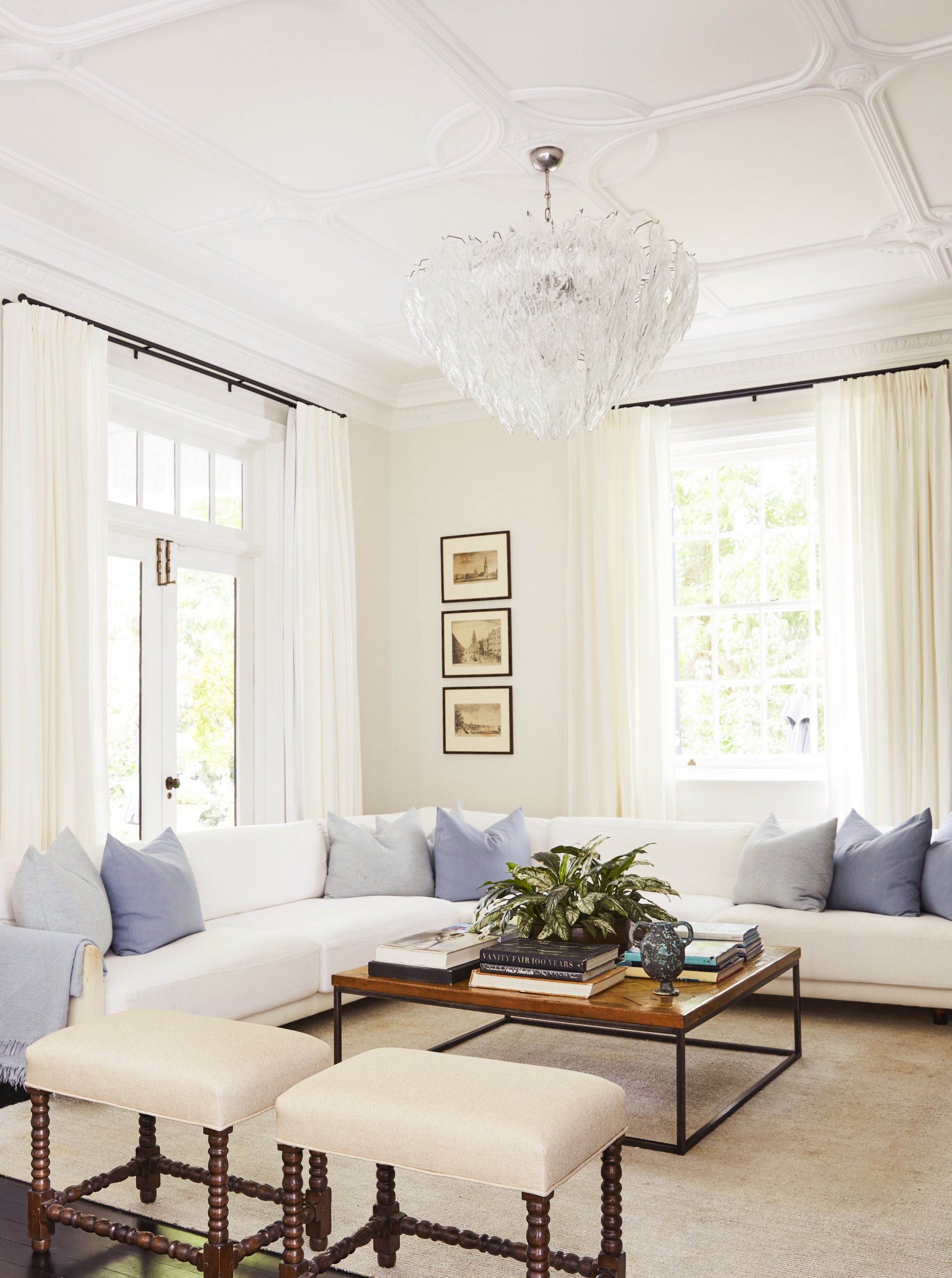 A classic white living room with a chandelier and L-shaped sofa.