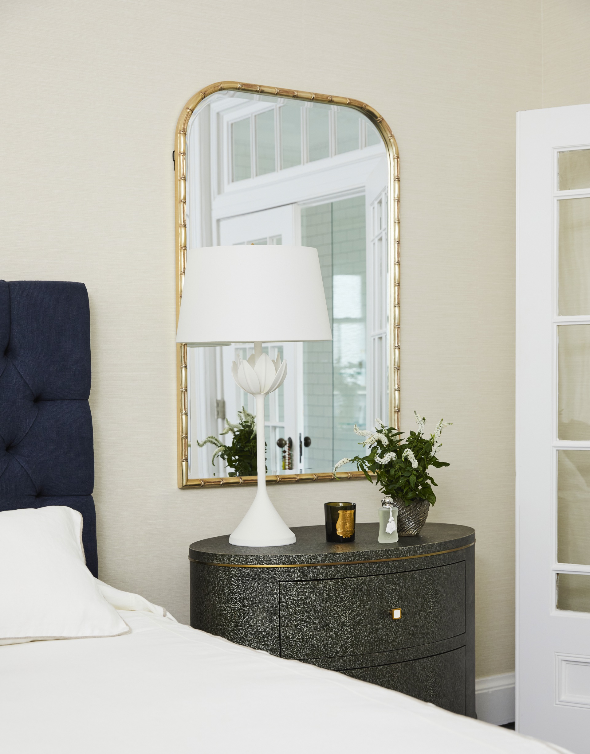 A gold arched mirror and black side table in the main bedroom.