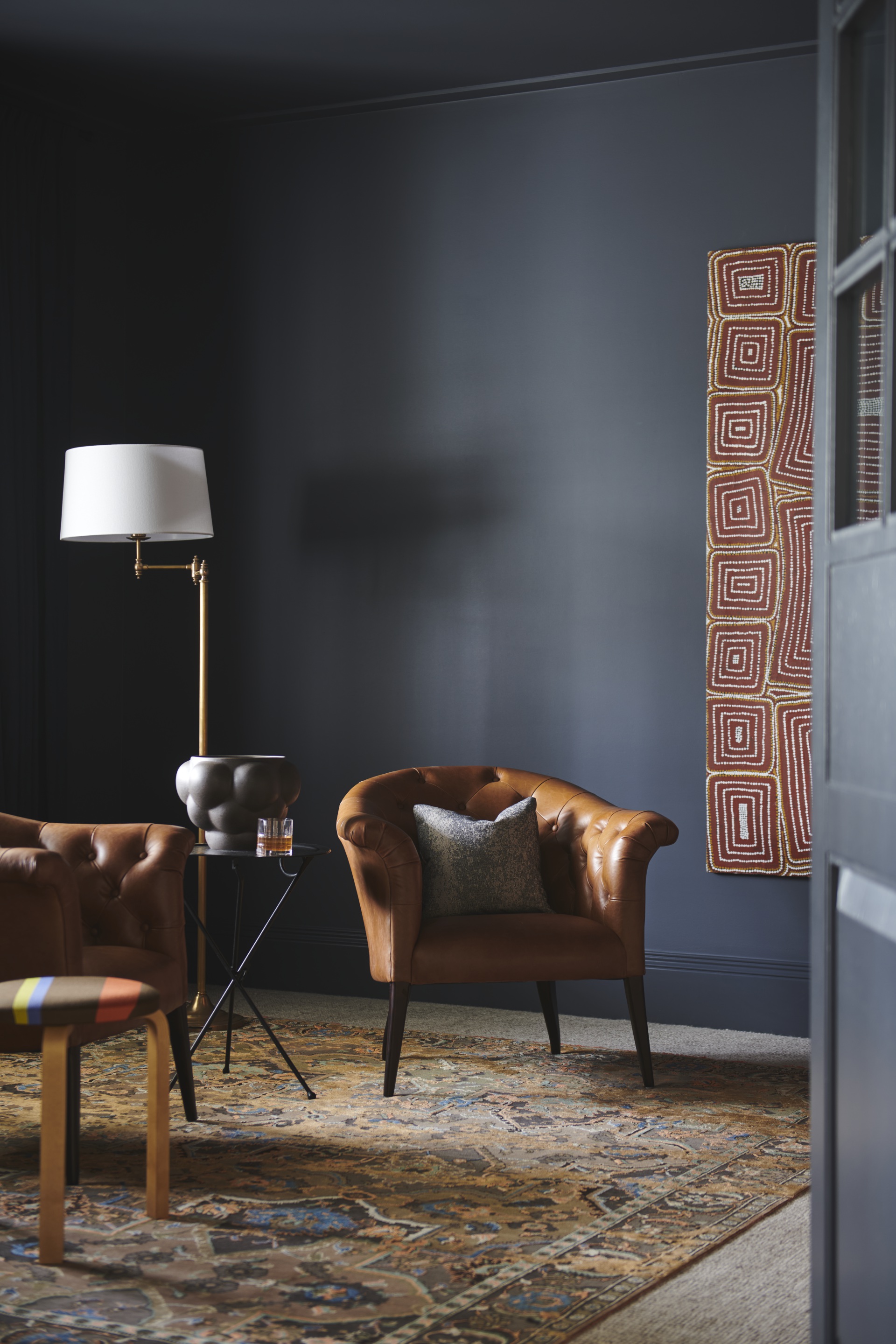 A navy study with two leather armchairs and a red swirl artwork.