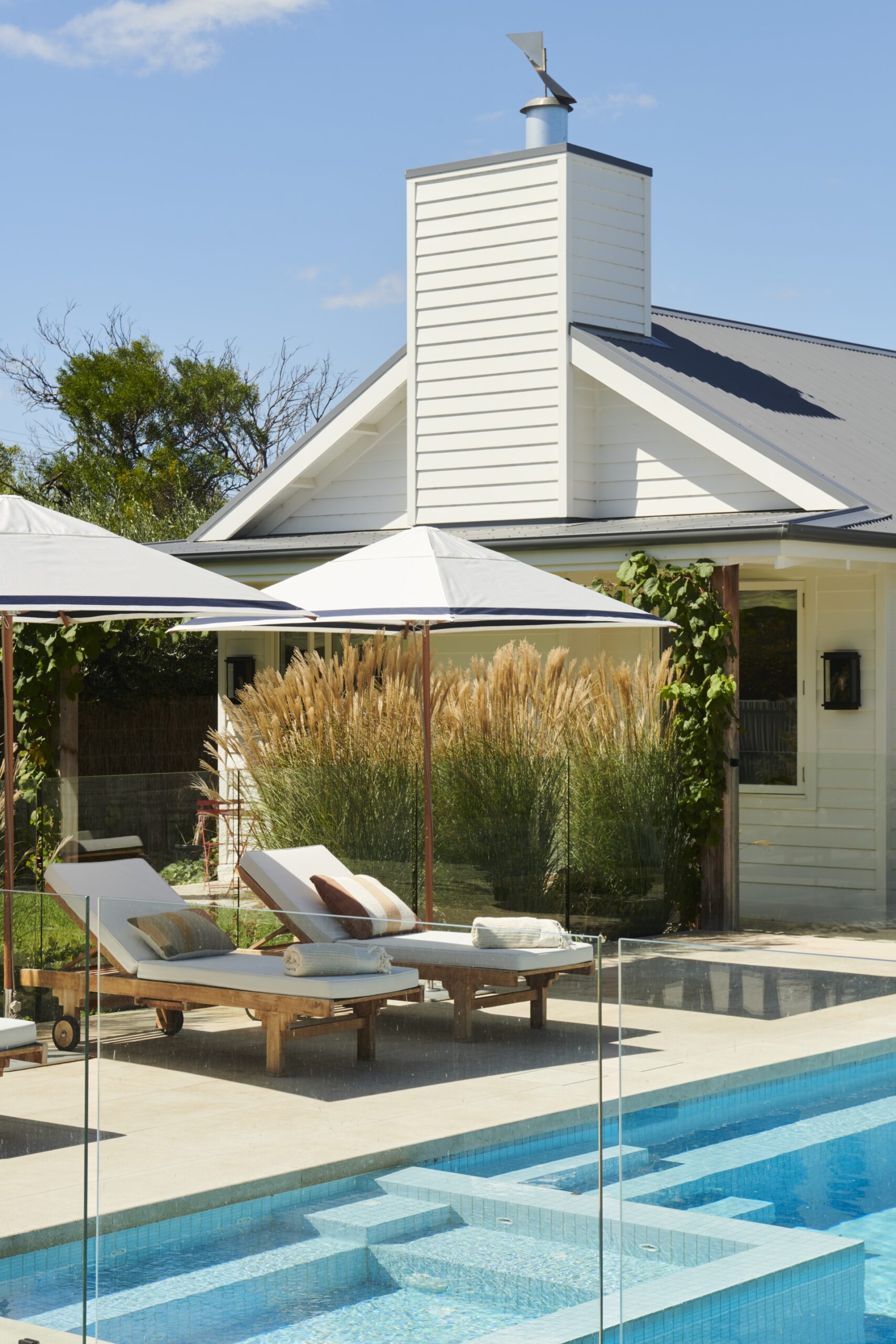 Two white pool loungers and parasols.