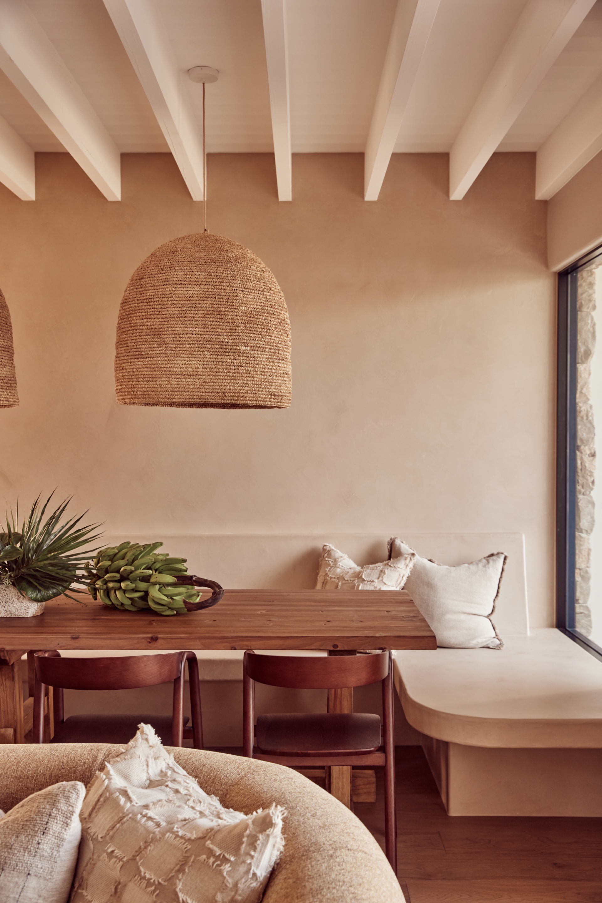 A timber banquette with a woven round pendant above.