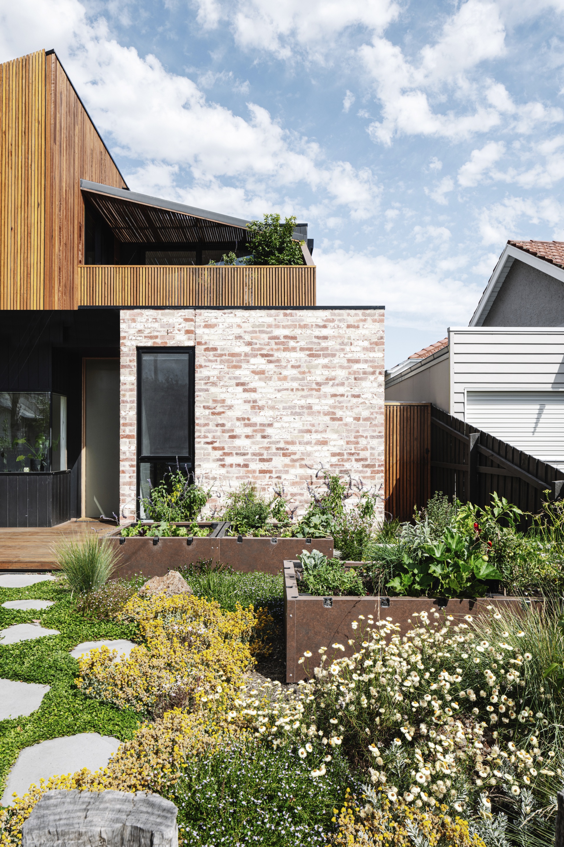 Seasonal produce grows in garden beds, clad in corten steel.