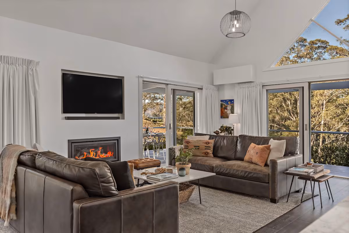 Kangaroo Valley accommodation white interior living room with leather lounges and cosy gas fireplace