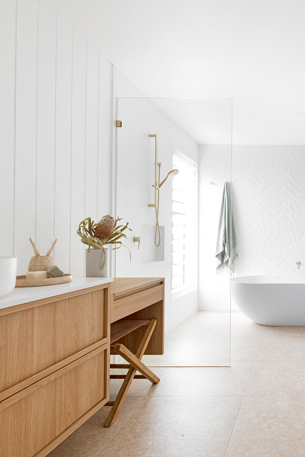 Coastal bathroom with timber vanity brass fittings and freestanding bathtub