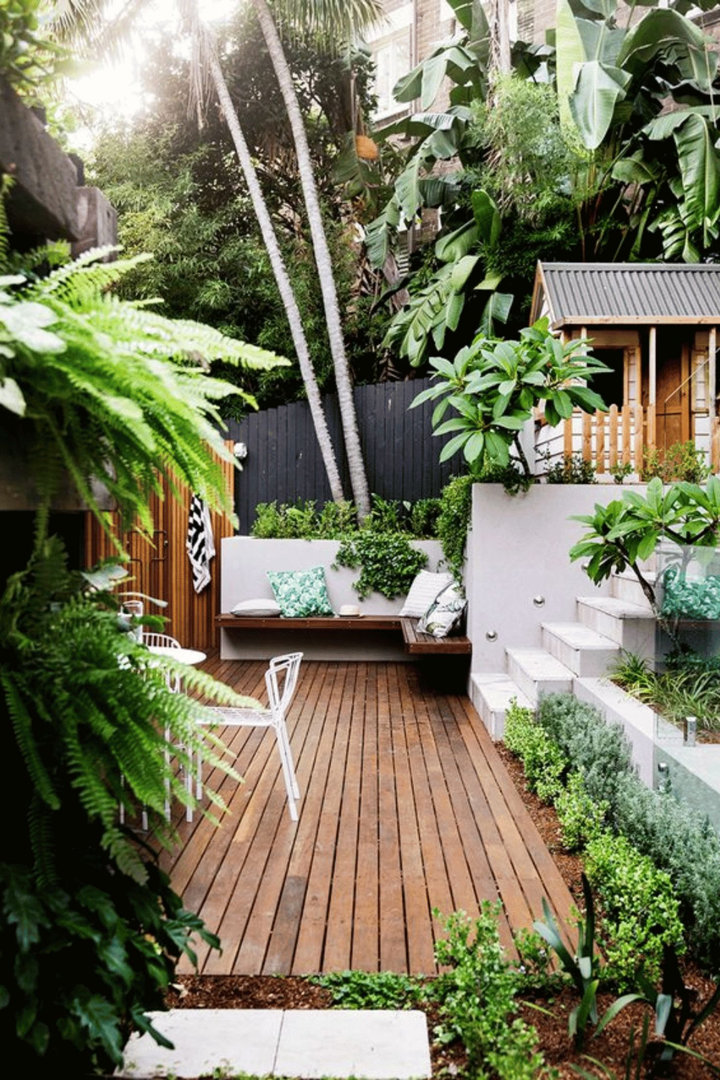 Small backyard with deck in courtyard and tropical plantings