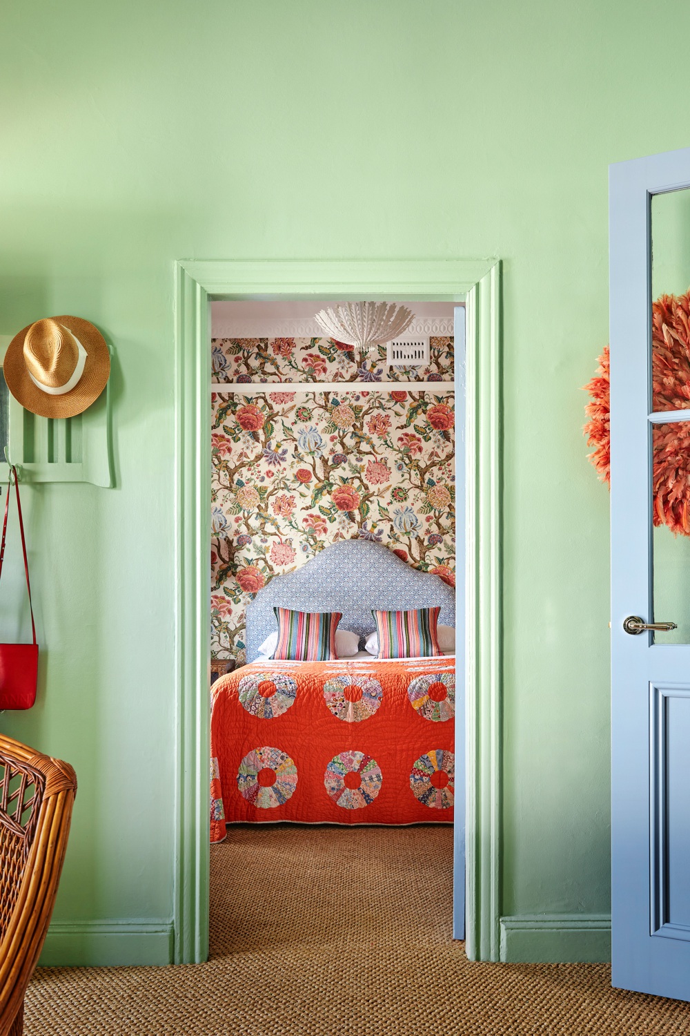 Colourful cottage bedroom with floral wallpaper and orange quilted coverlet